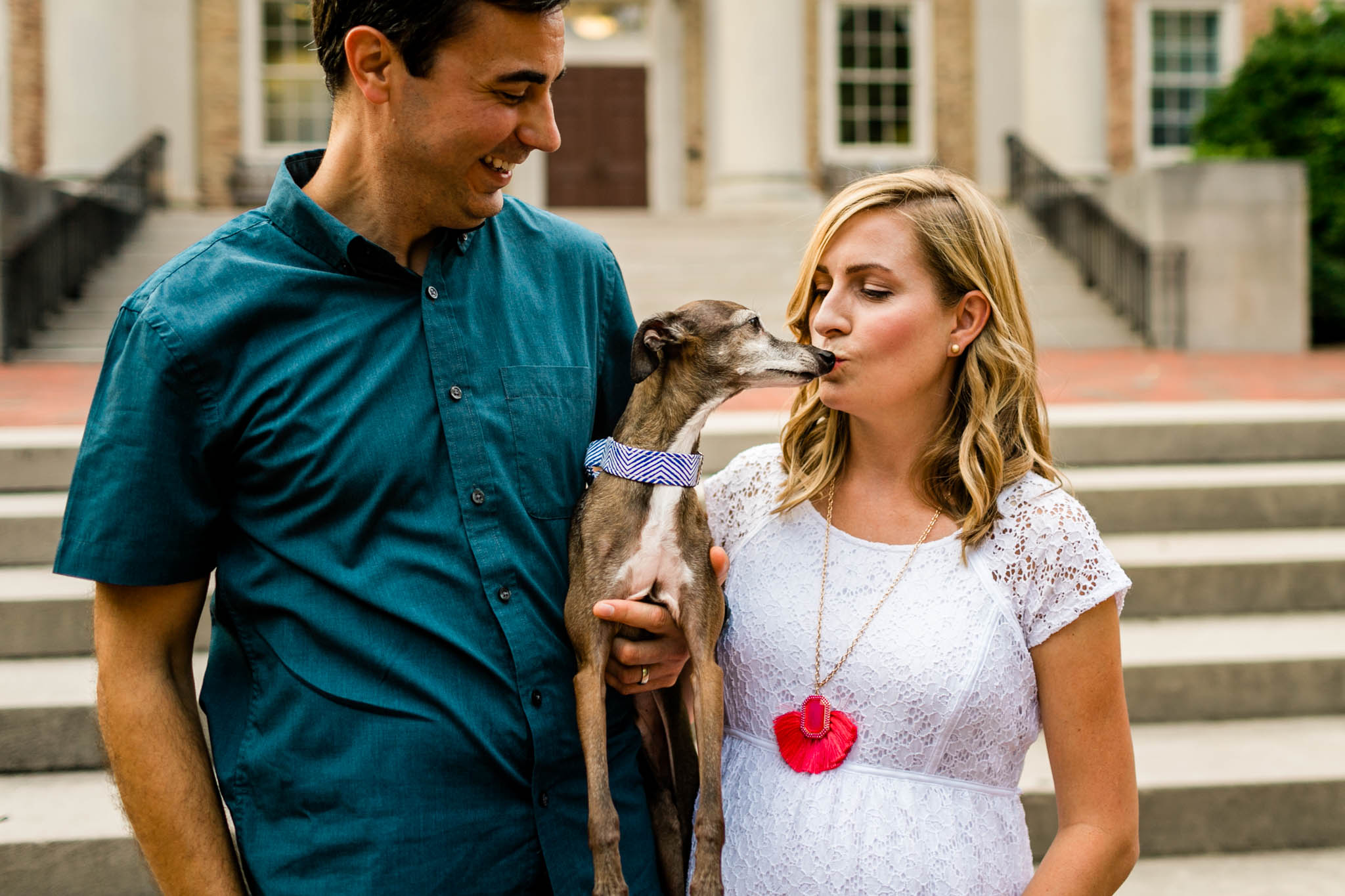 Chapel Hill Maternity Photographer at UNC | By G. Lin Photography | Couple holding dog in front of South Building and dog licking woman's face