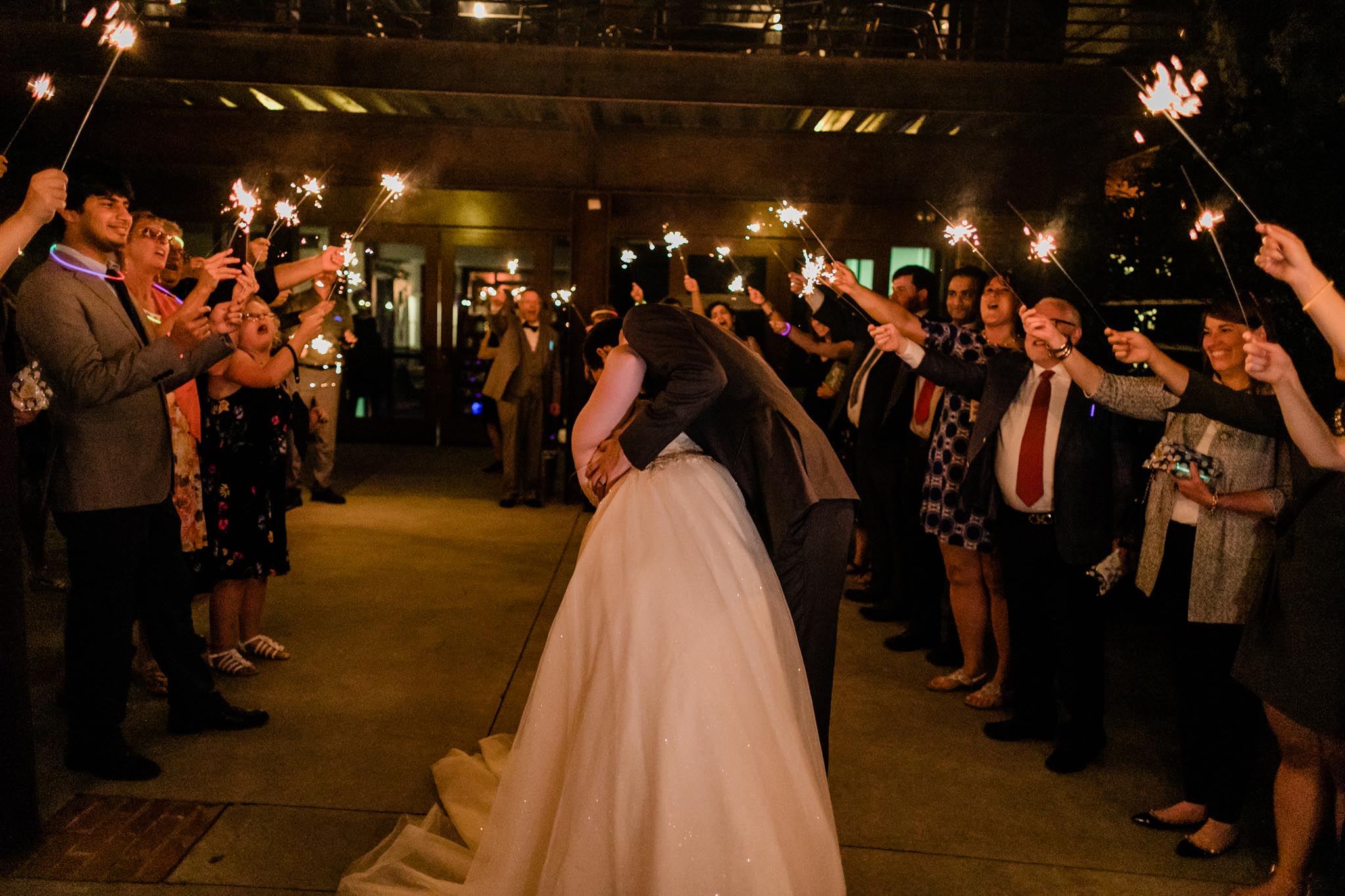 Haw River Ballroom Wedding | Durham Photographer | By G. Lin Photography | Groom kissing bride during sparkler sendoff