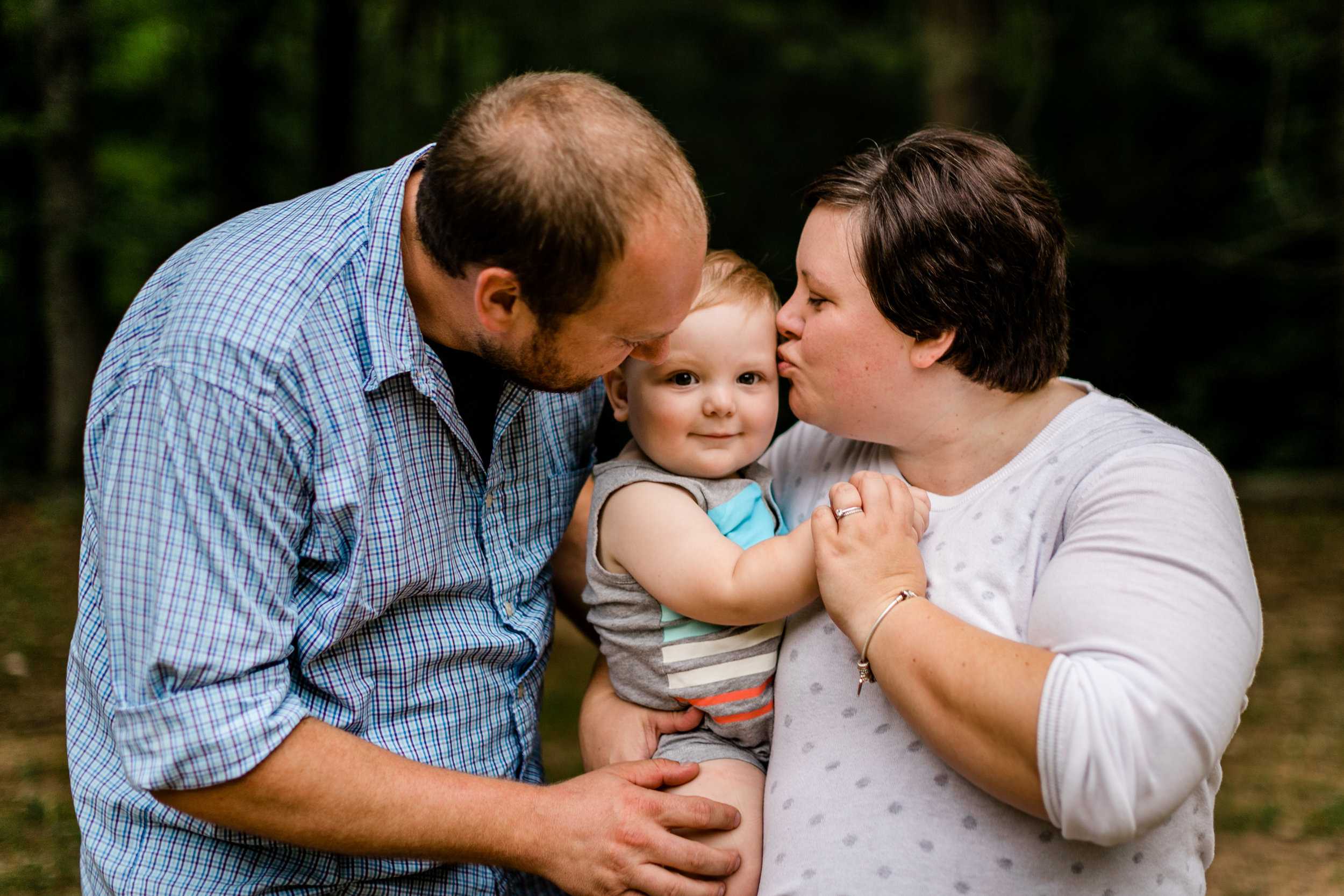 Durham Family Photographer | By G. Lin Photography | Outdoor portraits at Spruce Pine Lodge | Parents kissing son on cheeks