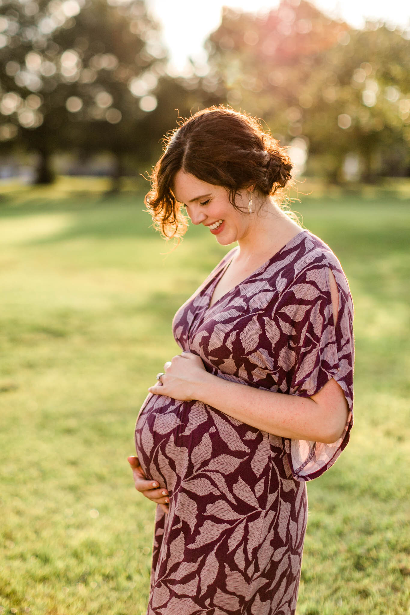 Raleigh Maternity Photography at Dix Park | By G. Lin Photography | Woman smiling and holding hands on baby bump