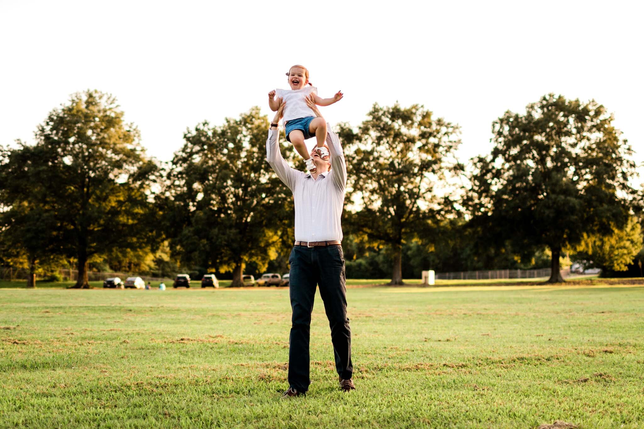 Raleigh Family Photographer at Dix Park | By G. Lin Photography | Dad tossing daughter in air at open field