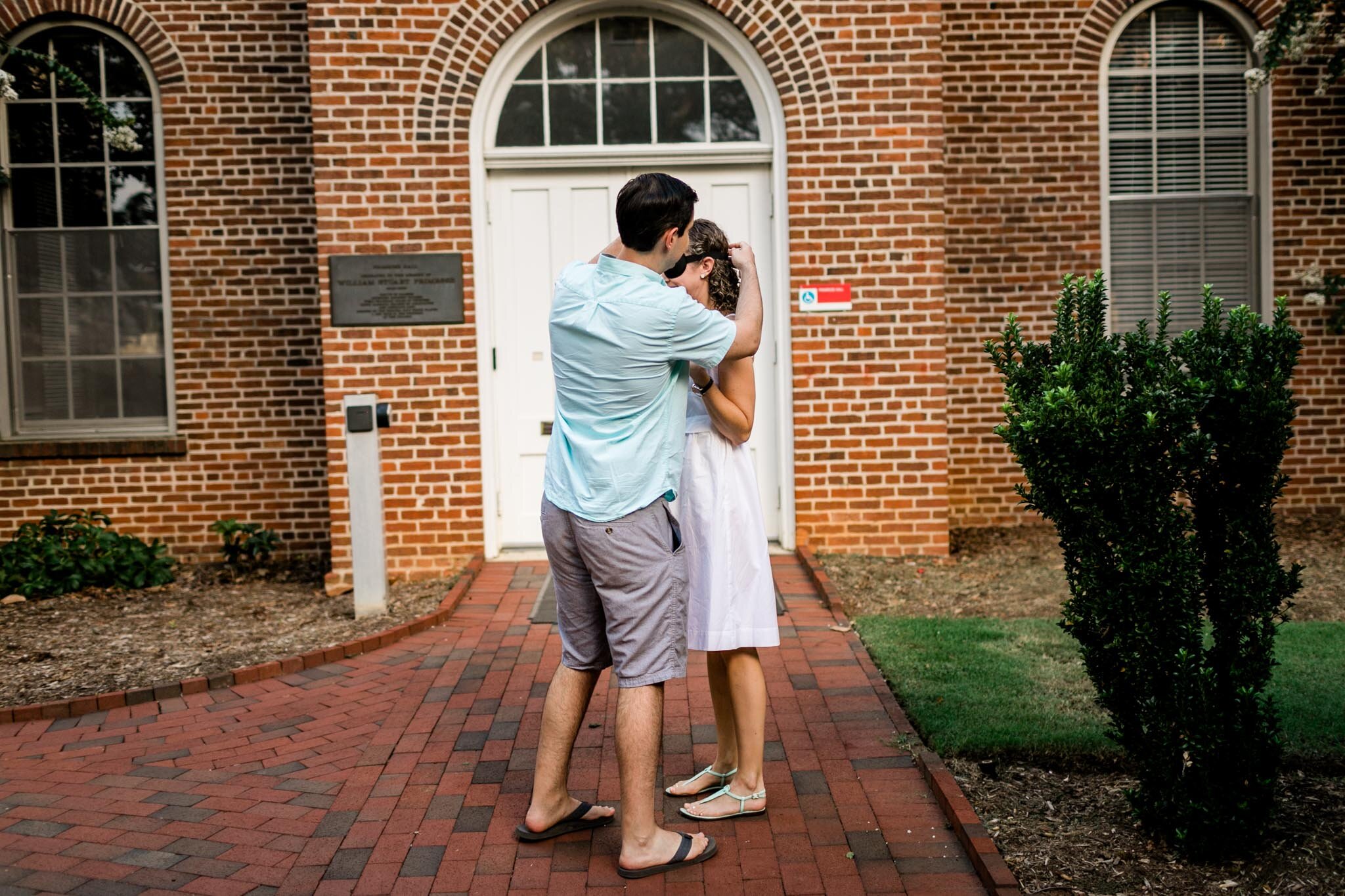 Engagement Photography at NC State | Primrose Hall | By G. Lin Photography | Raleigh Proposal Photographer | Man taking off blindfold from woman