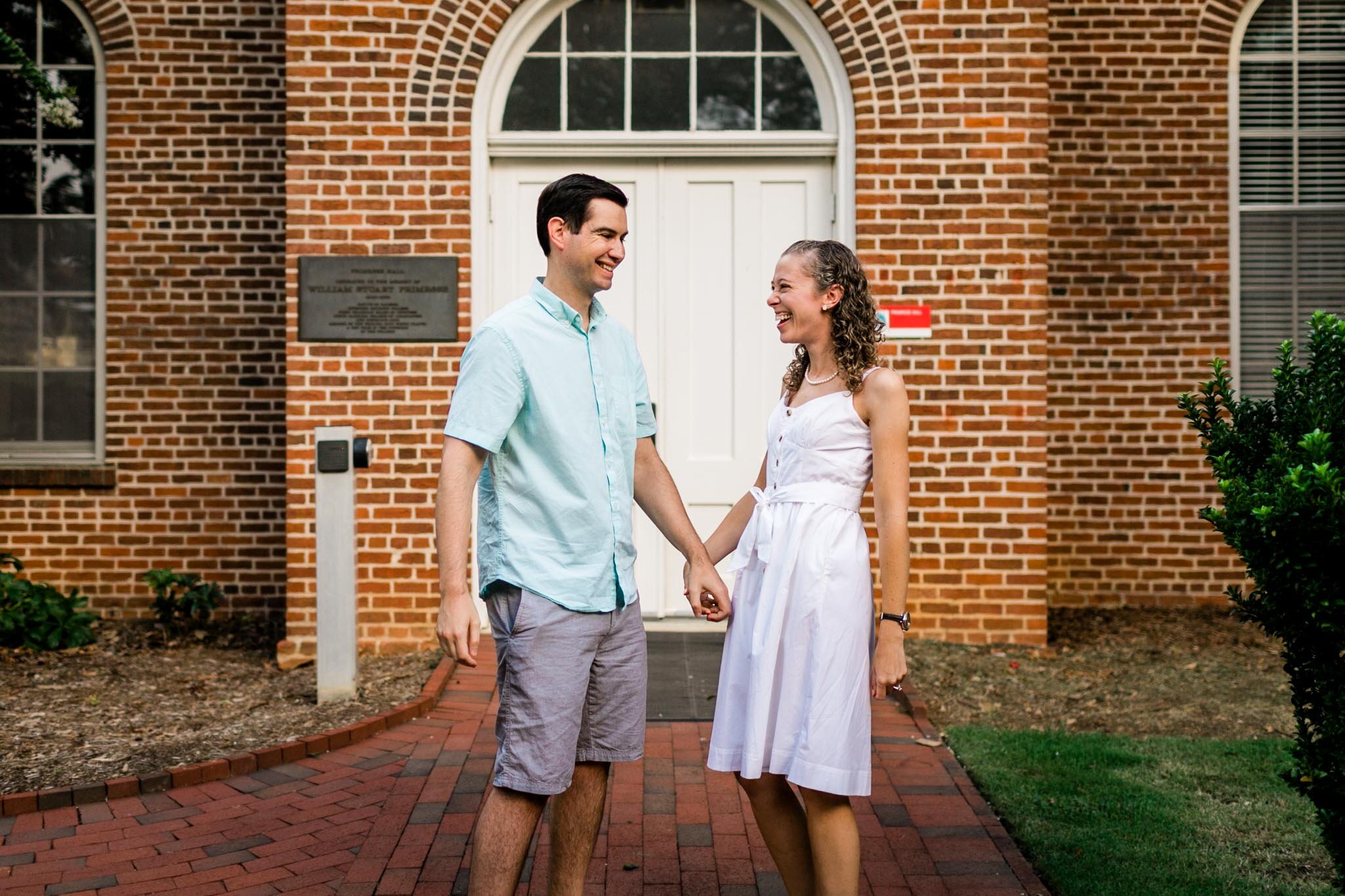 Raleigh Engagement Photographer | NC State University | By G. Lin Photography | Couple laughing together in front of building