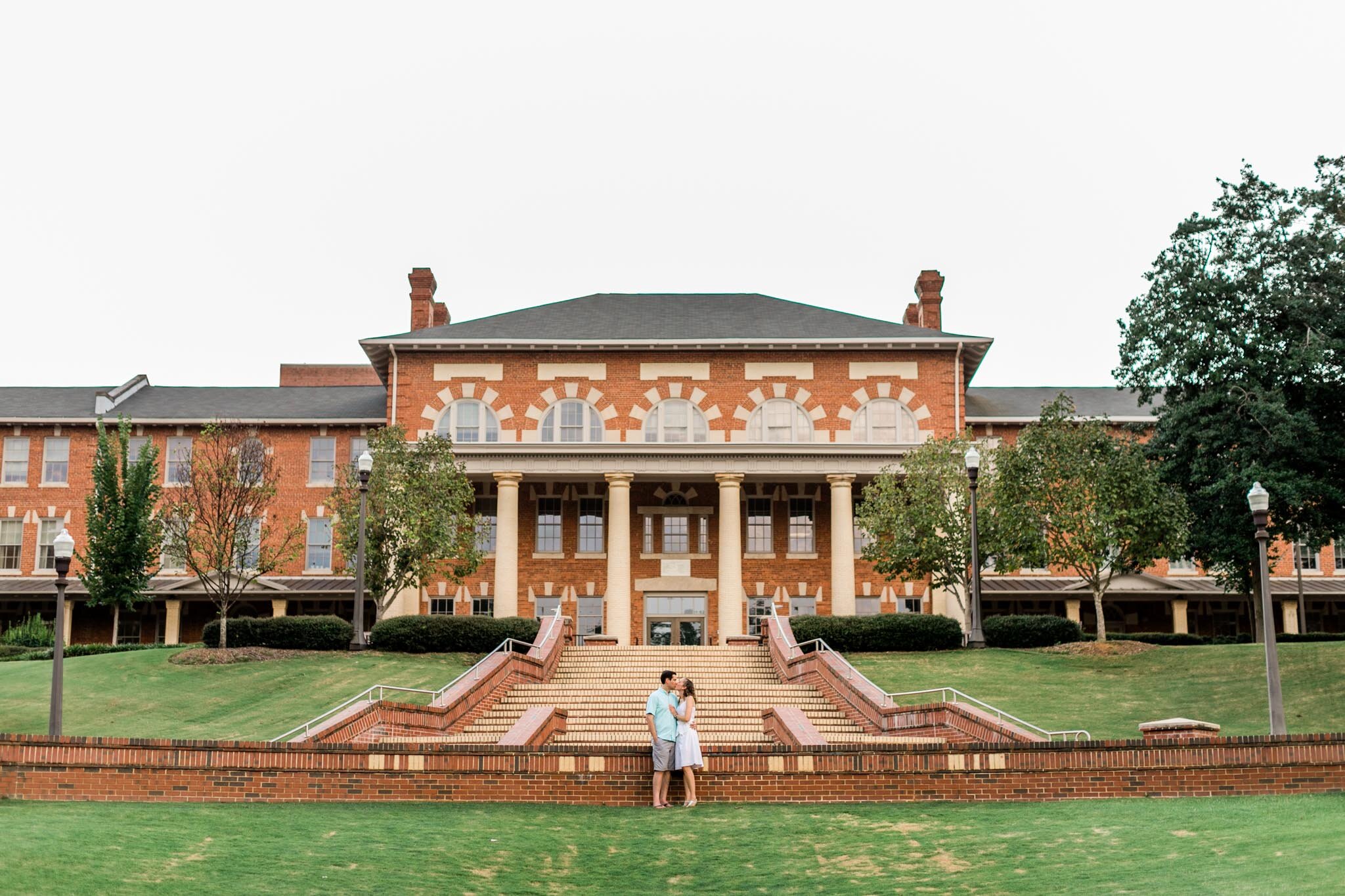 Raleigh Engagement Photographer | NC State University | By G. Lin Photography | Wide shot of couple standing in front of building