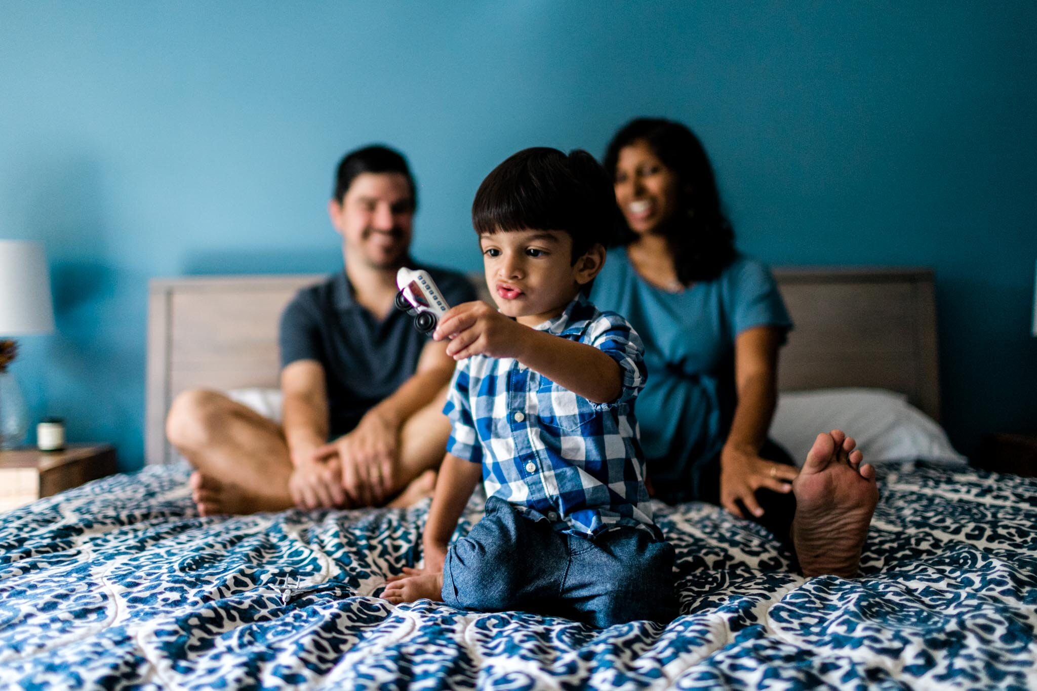 Raleigh Family Photographer | By G. Lin Photography | Boy playing with airplanes with family on bed
