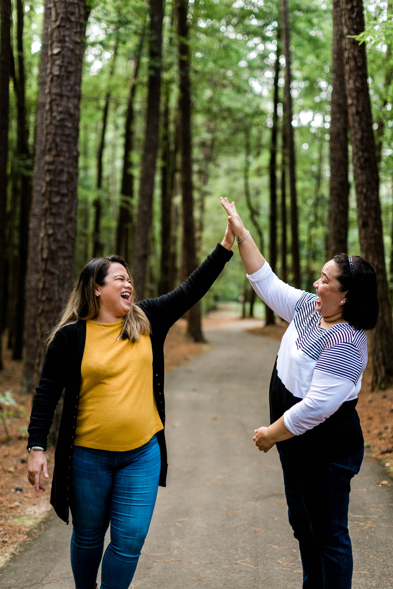 Two women giving high fives to each other | Durham Photographer | By G. Lin Photography | Portrait at Umstead Park