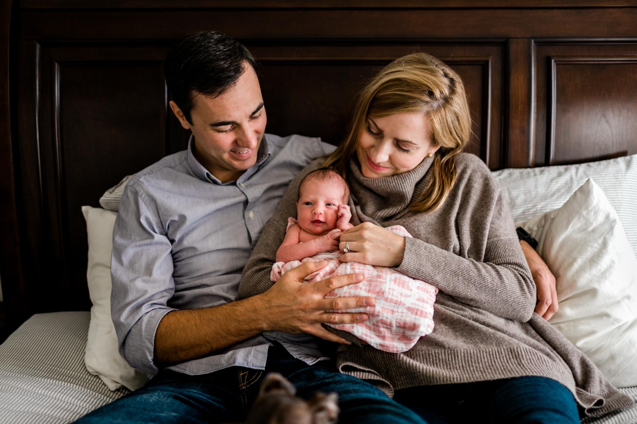 Durham Newborn Photographer | By G. Lin Photography | Parents snuggling on bed with baby girl