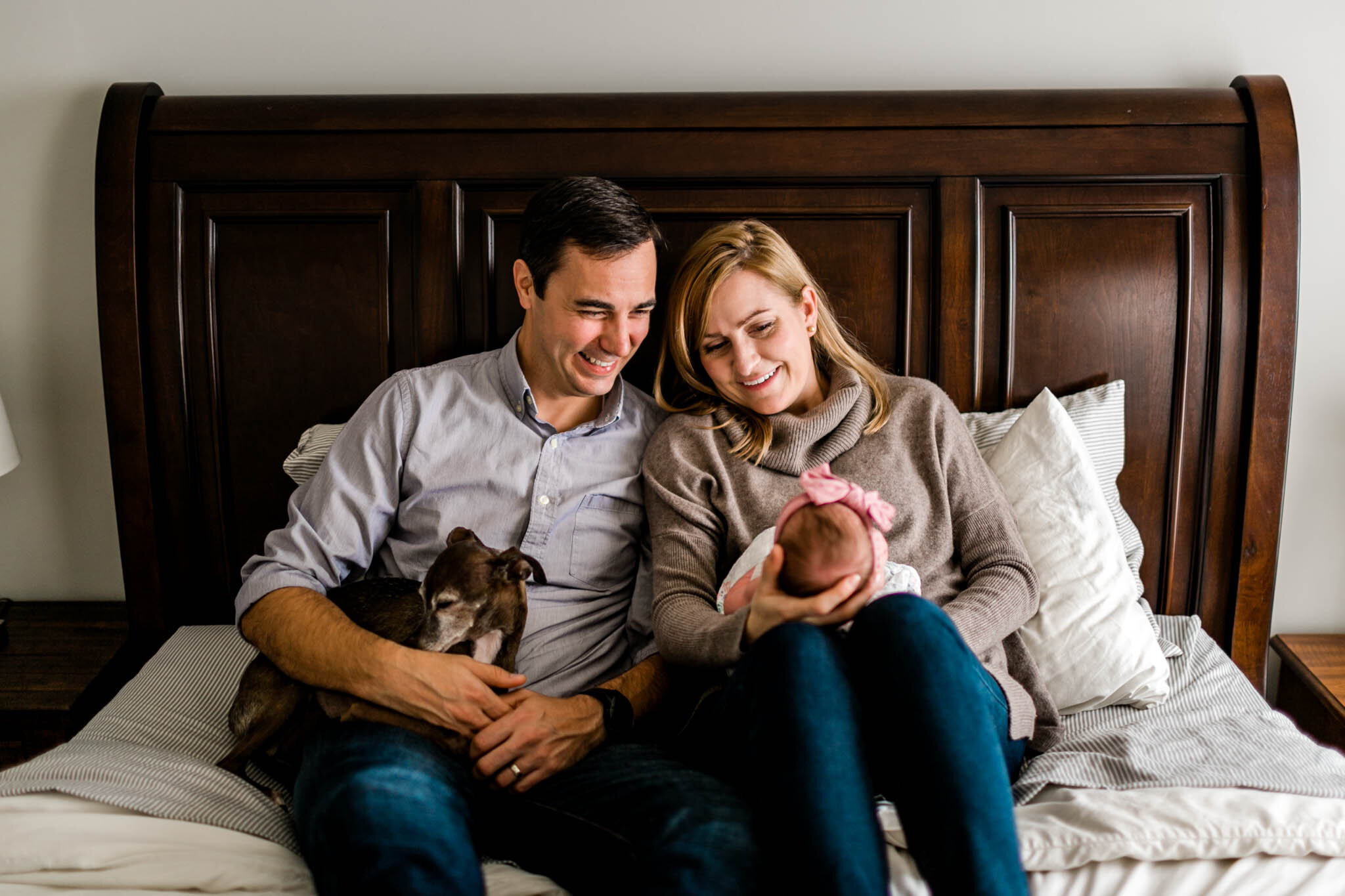Durham Newborn Photographer | By G. Lin Photography | Parents holding baby girl on bed and smiling