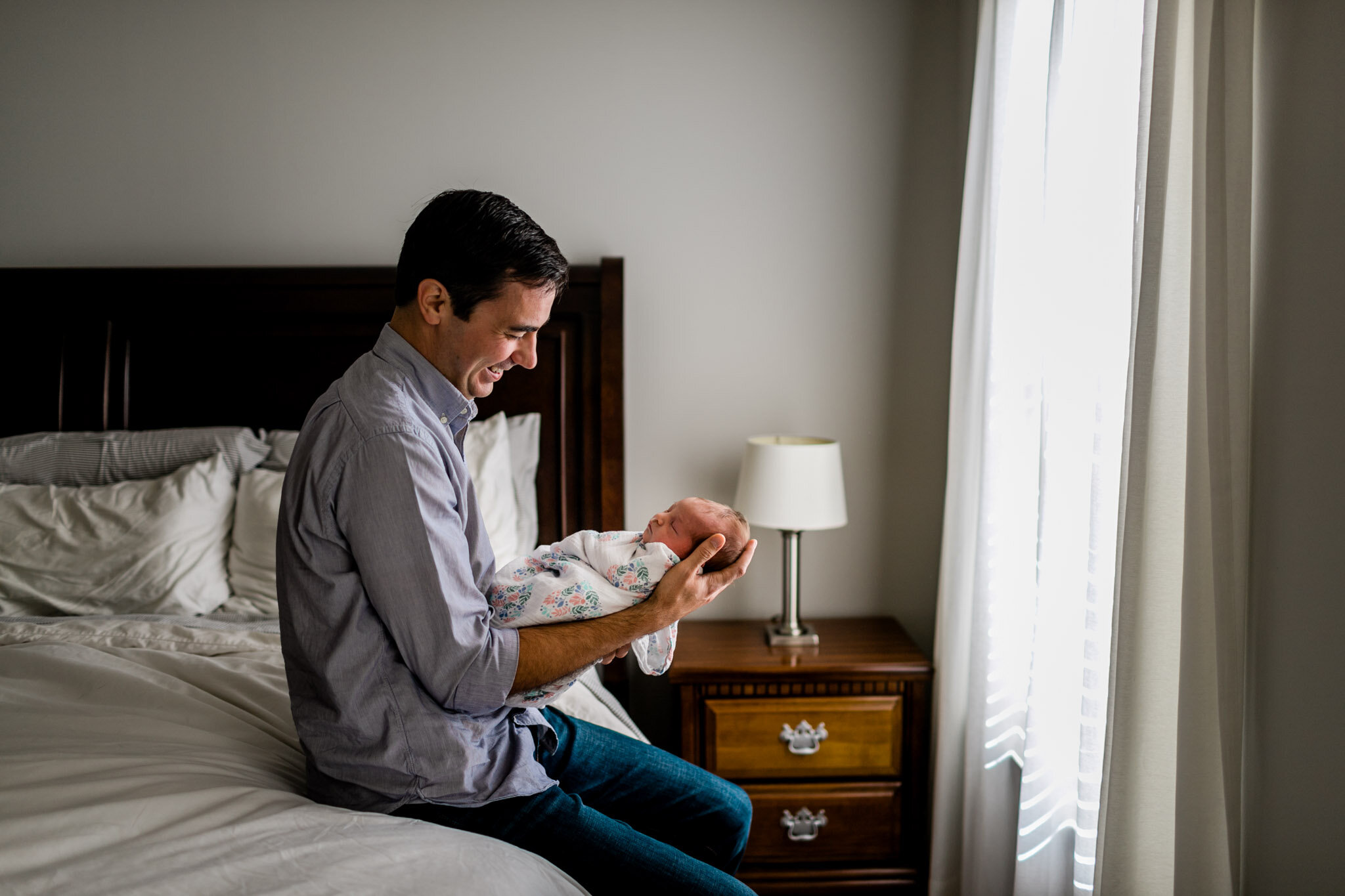 Durham Newborn Photographer | By G. Lin Photography | Father holding baby girl and sitting on bed