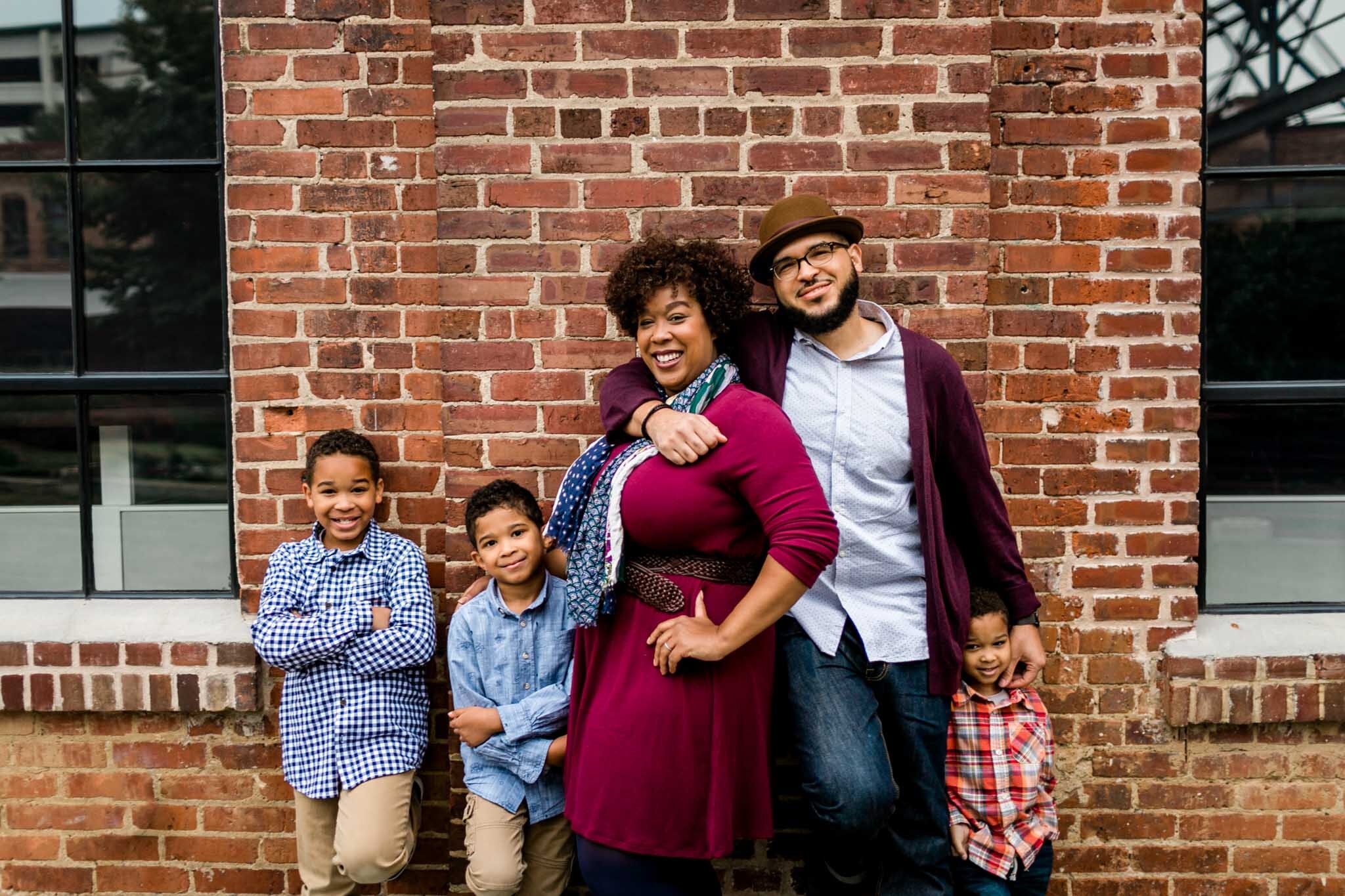 Durham Family Photographer | By G. Lin Photography | Family posing against brick wall at American Tobacco Campus