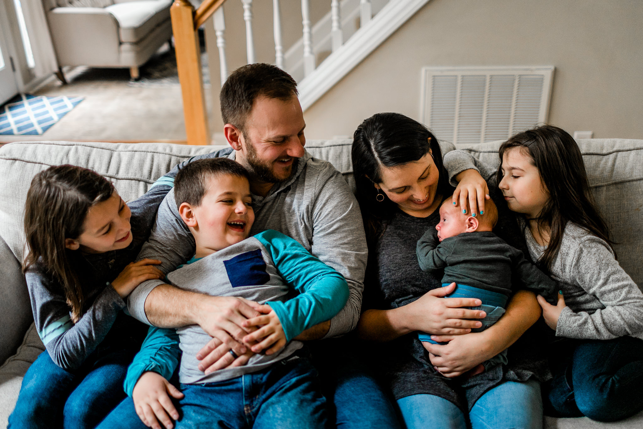 Family sitting on couch together and laughing | Raleigh Newborn Photographer | Lifestyle Newborn Shoot | By G. Lin Photography