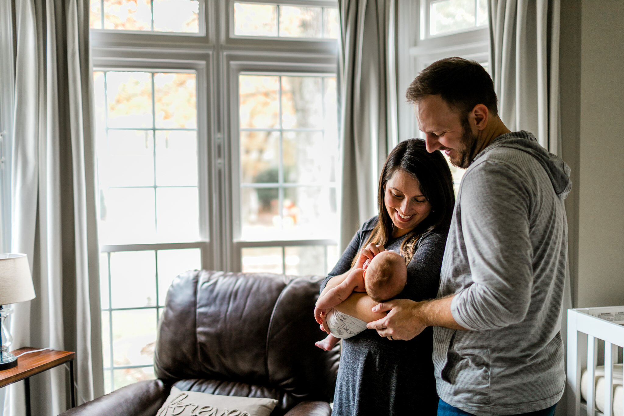Raleigh Newborn Photography | Lifestyle Session at Home | By G. Lin Photography | Parents holding baby boy by window
