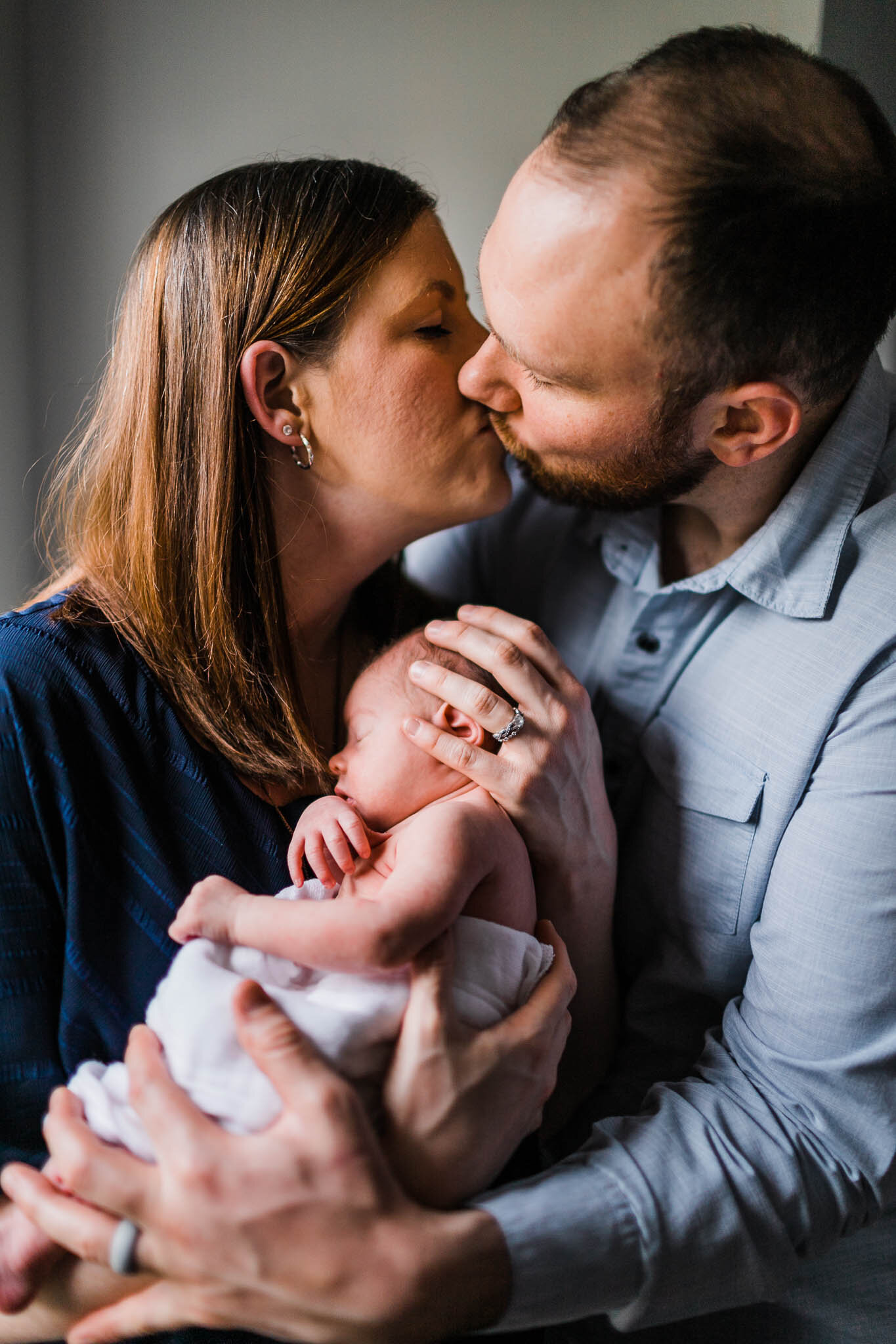 Raleigh Newborn Photographer | By G. Lin Photography | Parents giving each other a kiss while holding baby