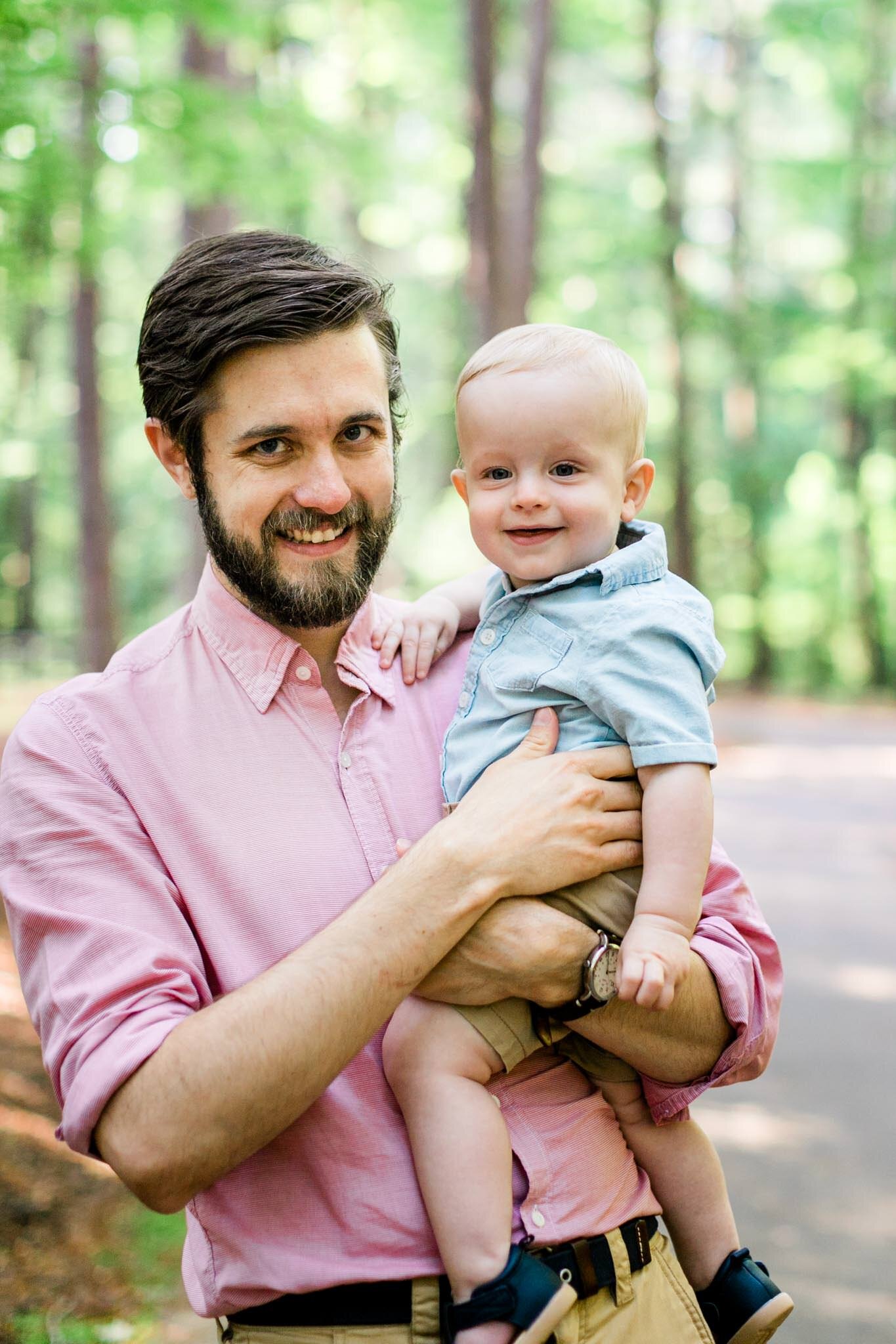 Raleigh Family Photographer | By G. Lin Photography | Umstead Park | Father holding son in arms outdoors in forest