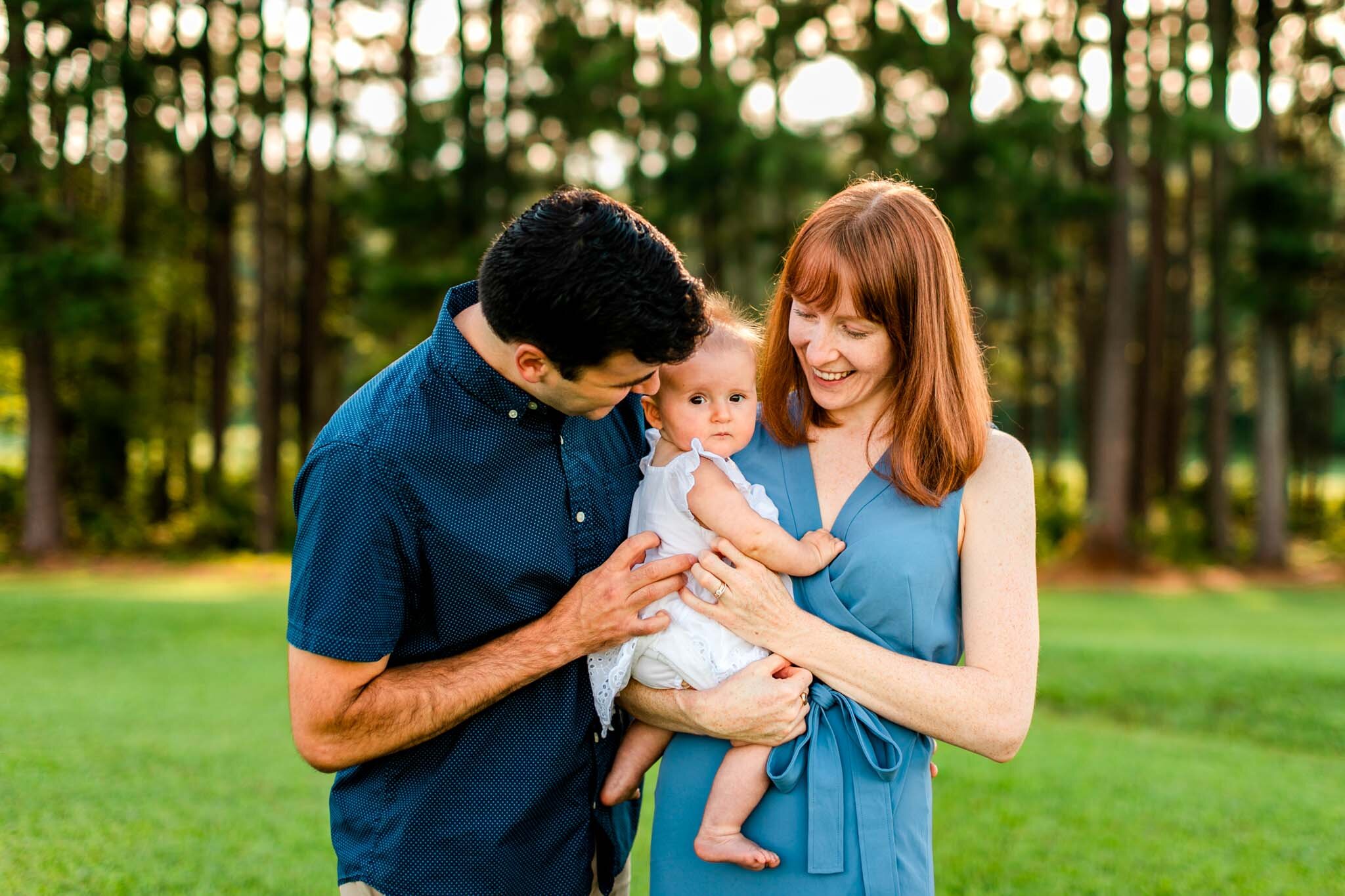 Raleigh Family Photographer | By G. Lin Photography | Dix Park | Candid outdoor shot of mom and dad holding baby