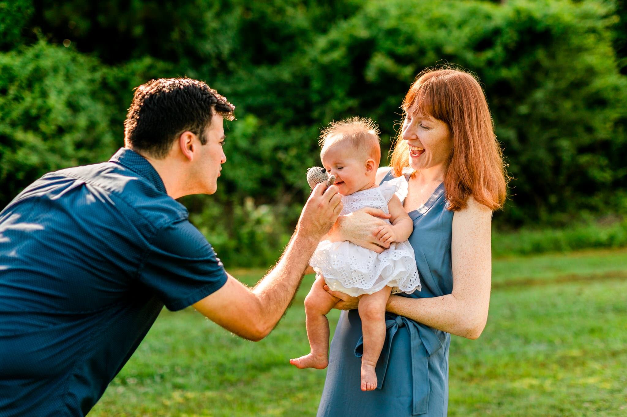 Raleigh Family Photographer | By G. Lin Photography | Dix Park | Parents holding and playing with baby girl outside and laughing