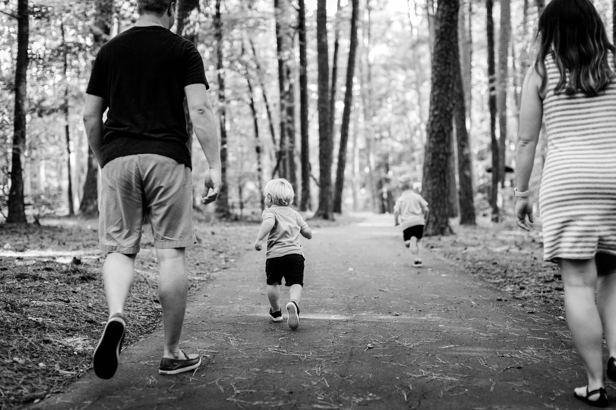 Raleigh Family Photographer | Umstead Park | By G. Lin Photography | Black and white photo of family walking and children running
