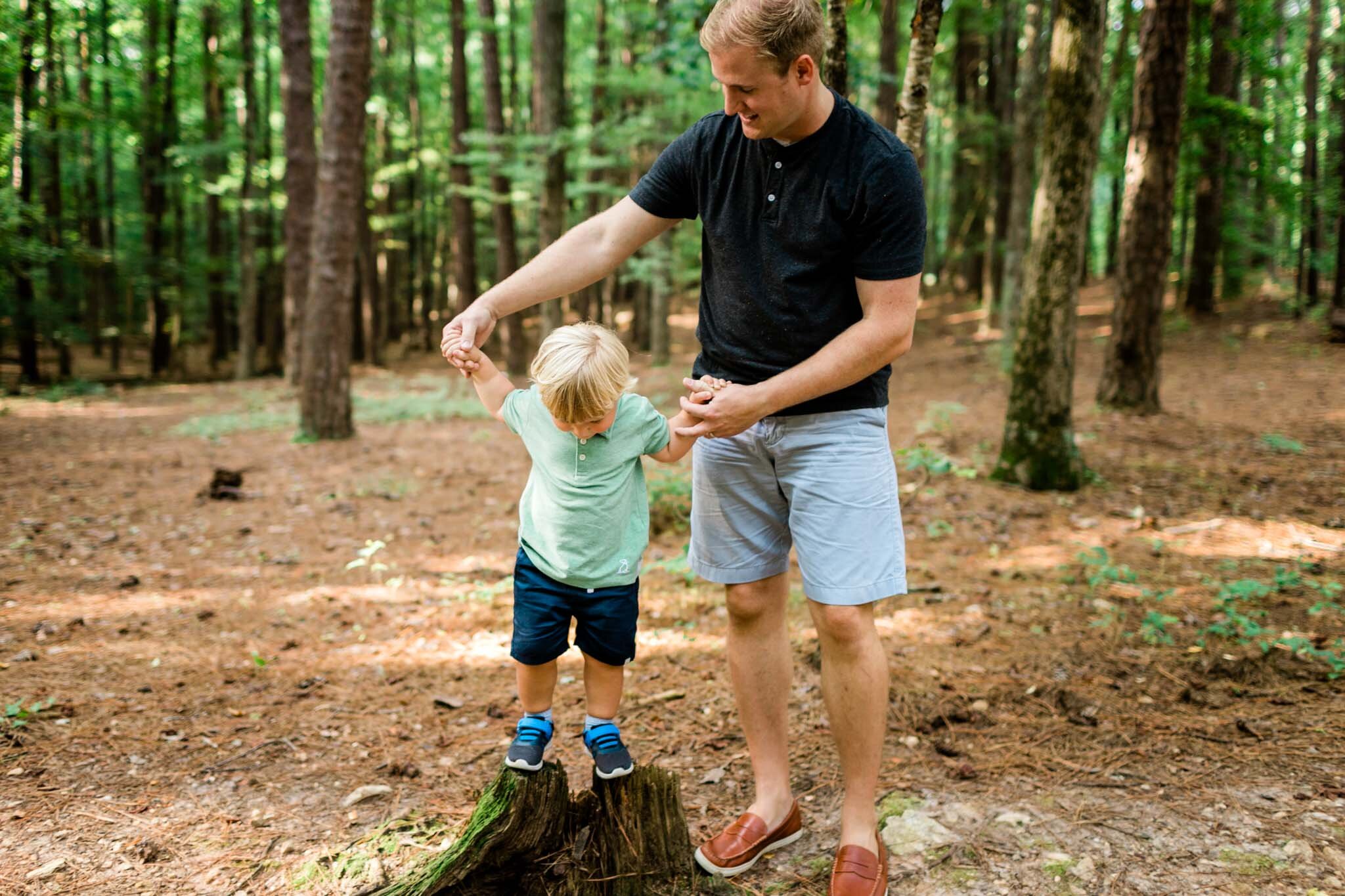 Raleigh Family Photographer | Umstead Park | By G. Lin Photography | Dad helping young toddler boy on tree stump