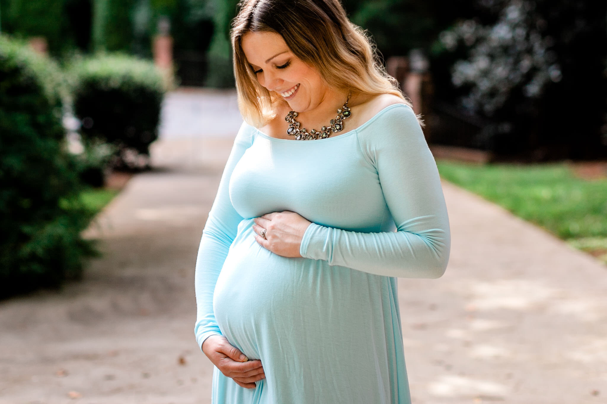 Raleigh Maternity Photographer | By G. Lin Photography | Woman smiling and touching baby bump
