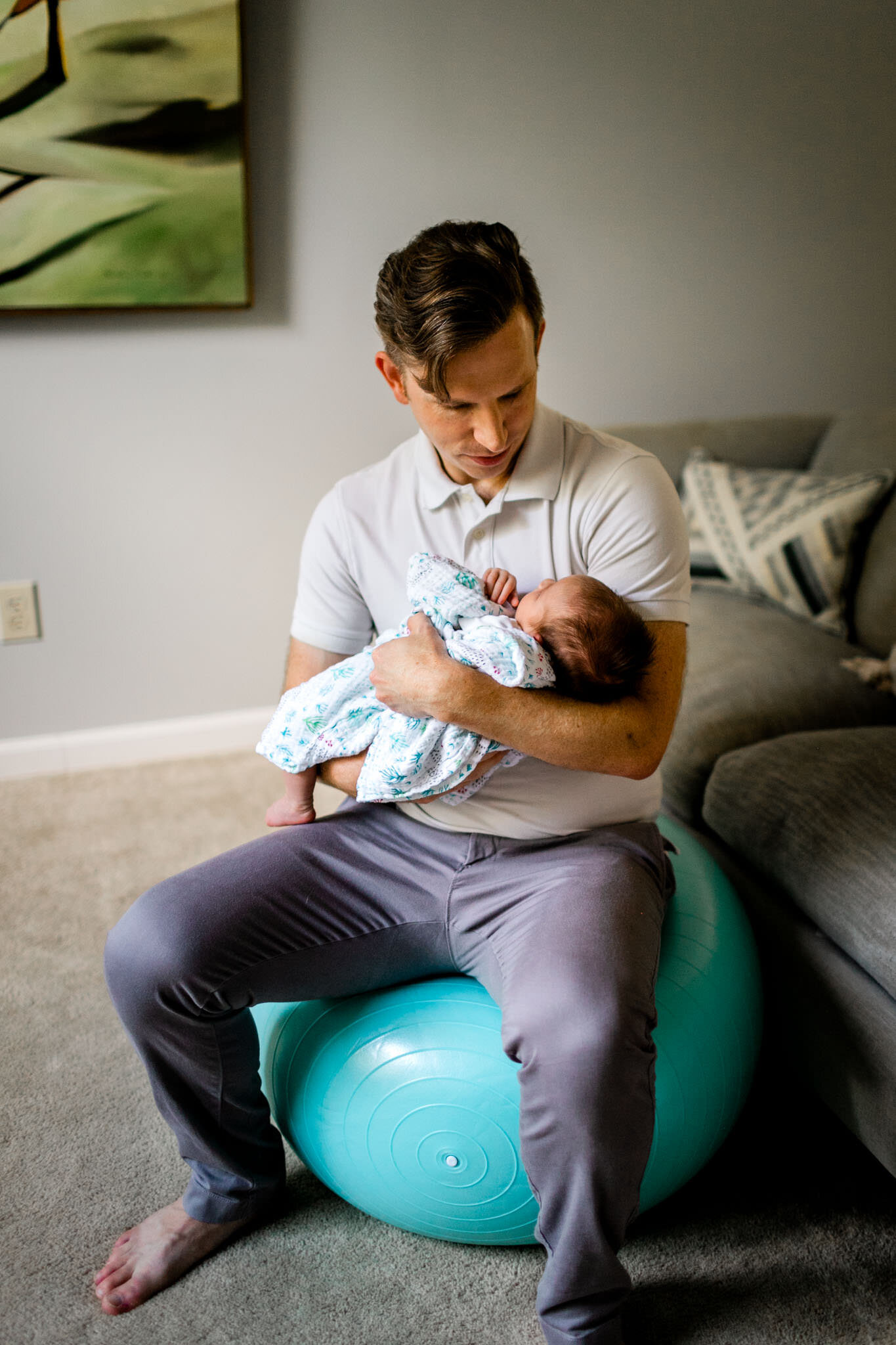 Raleigh Newborn Photographer | By G. Lin Photography | Father holding baby while sitting on yoga ball