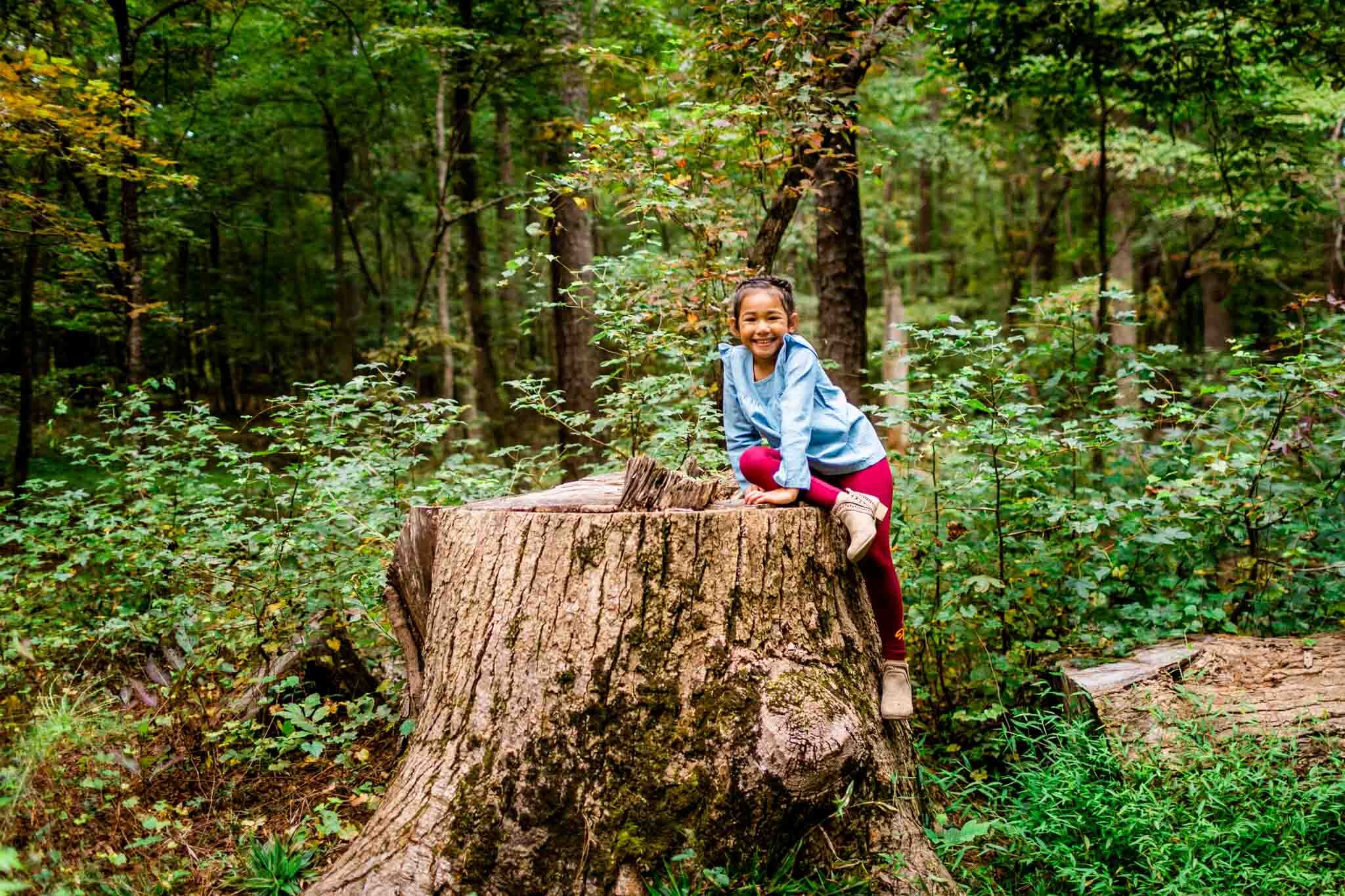 Raleigh Family Photographer | By G. Lin Photography | Umstead Park | Young girl sitting on top of large tree stump