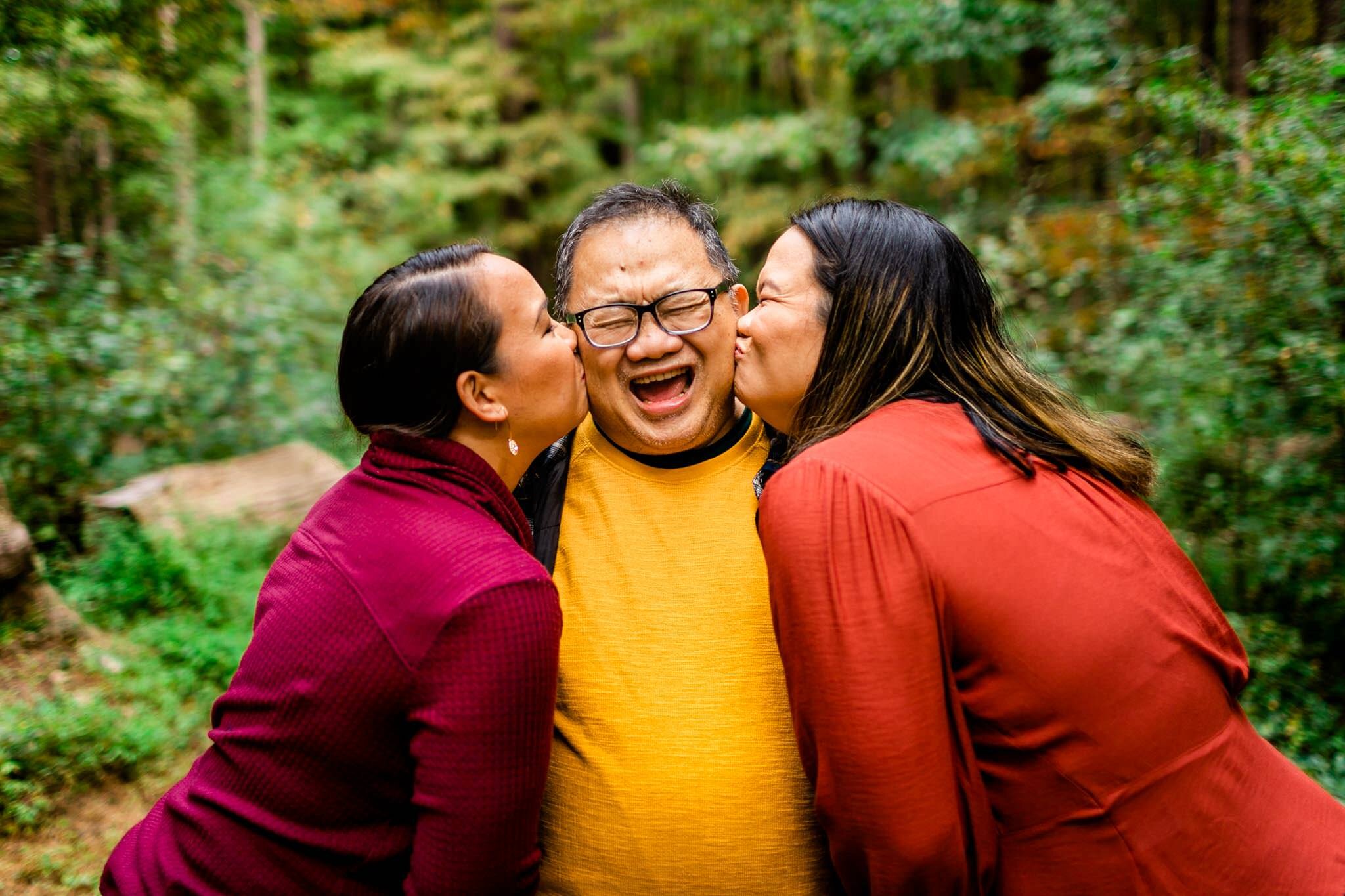 Raleigh Family Photographer | By G. Lin Photography | Umstead Park | Two daughters giving dad a kiss on the cheek