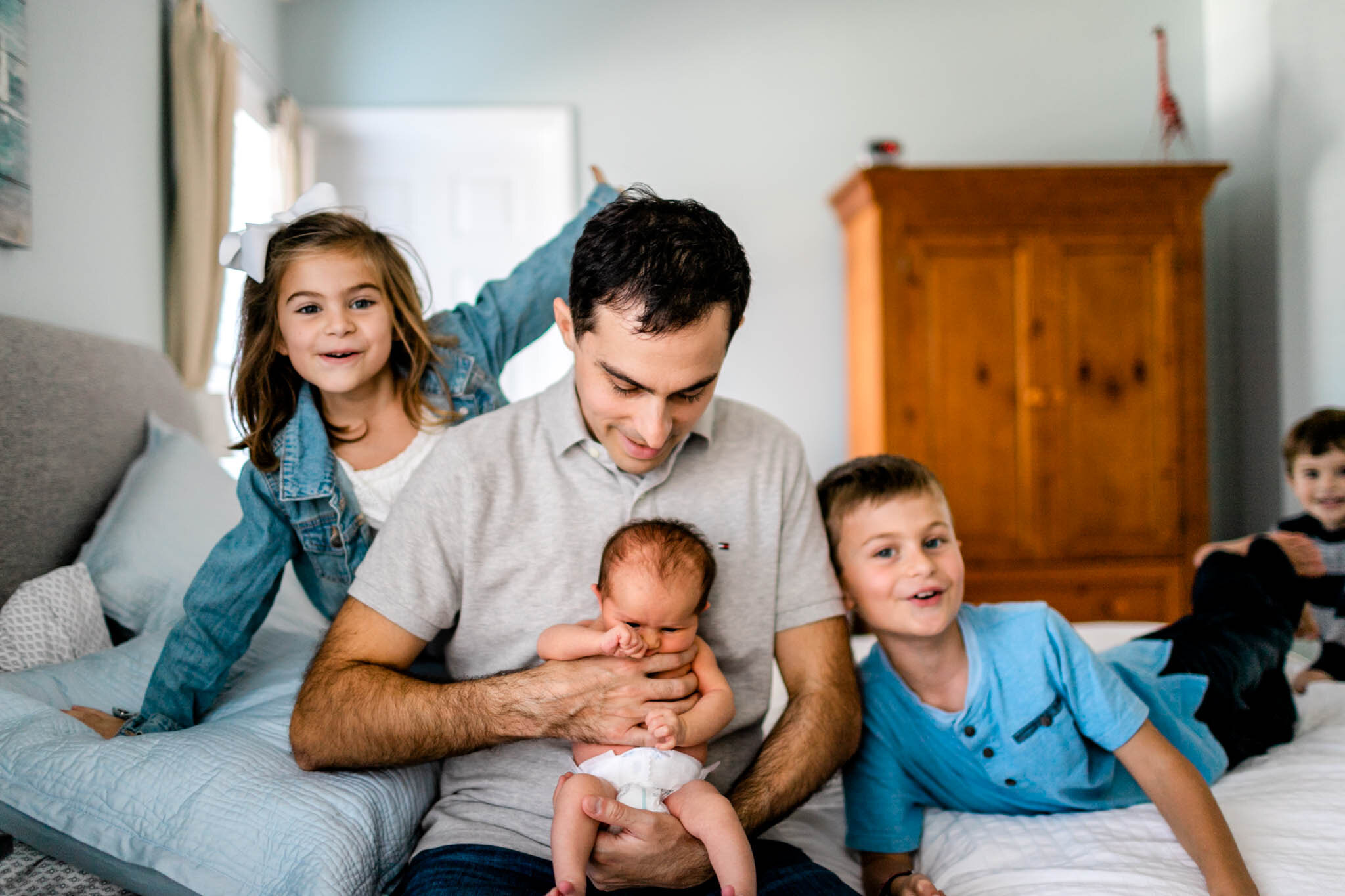 Raleigh Newborn Photographer | By G. Lin Photography | Kids and dad sitting on bed with baby