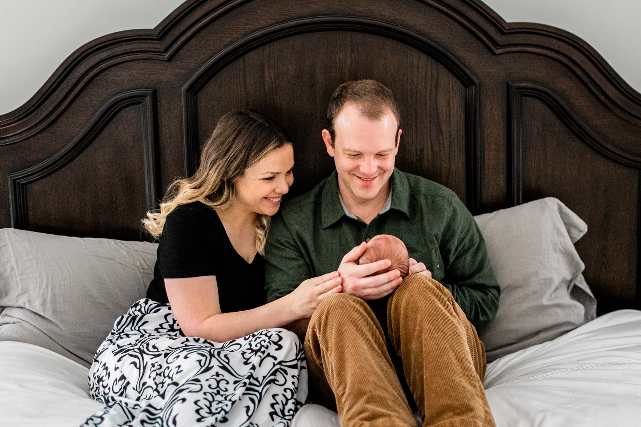 Raleigh Newborn Photographer | By G. Lin Photography | Mother and father sitting on bed with baby boy