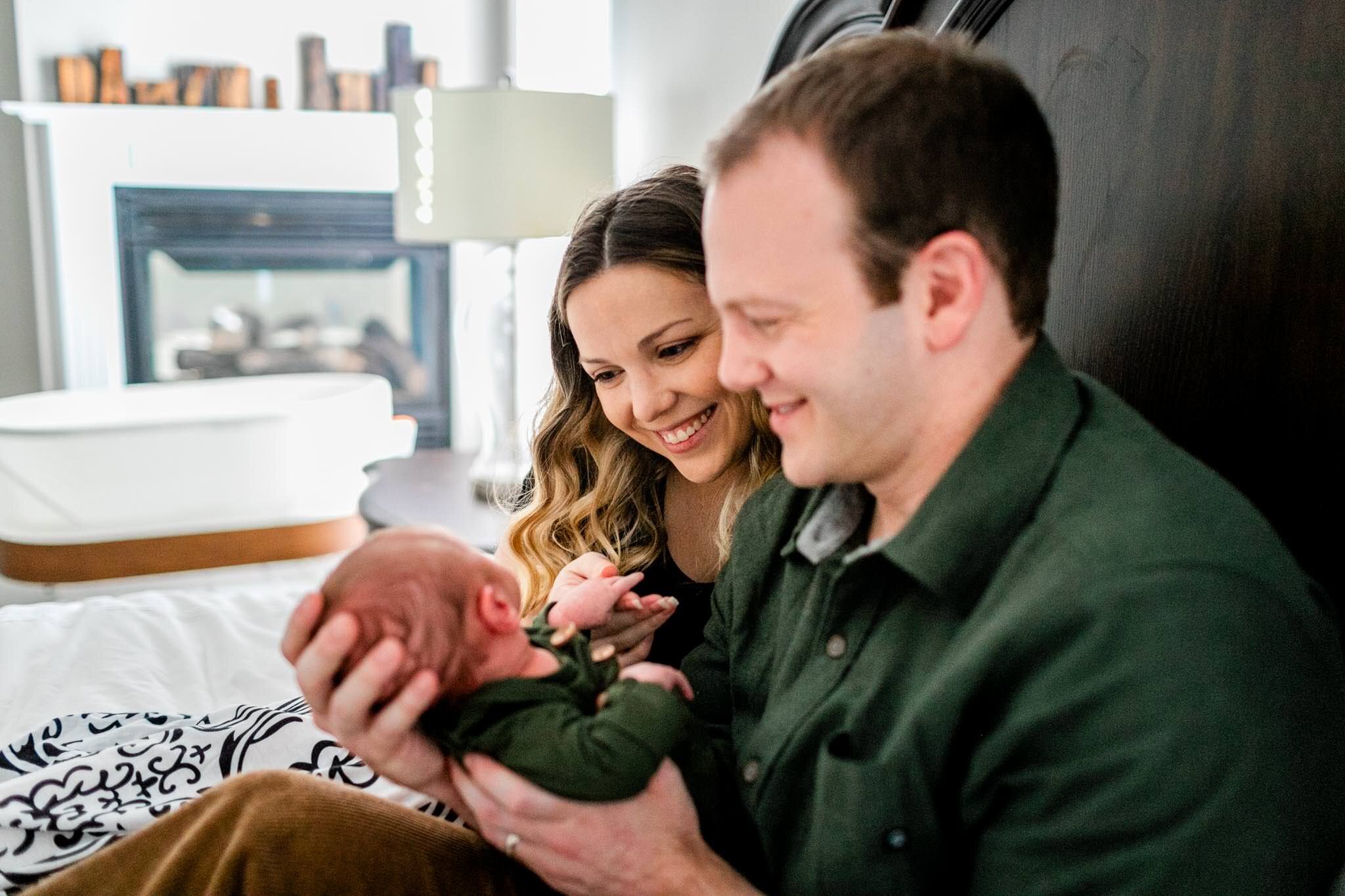 Raleigh Newborn Photographer | By G. Lin Photography | Mother and father looking at baby boy and sitting on bed