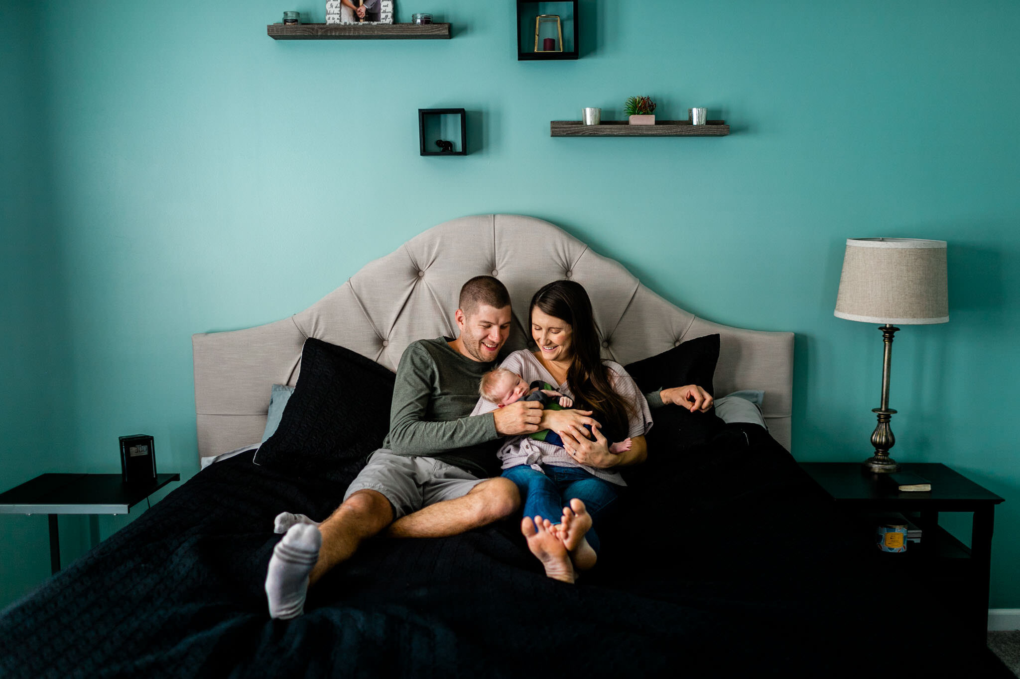 Durham Newborn Photographer | By G. Lin Photography | Lifestyle newborn photo at home with parents sitting on bed with baby