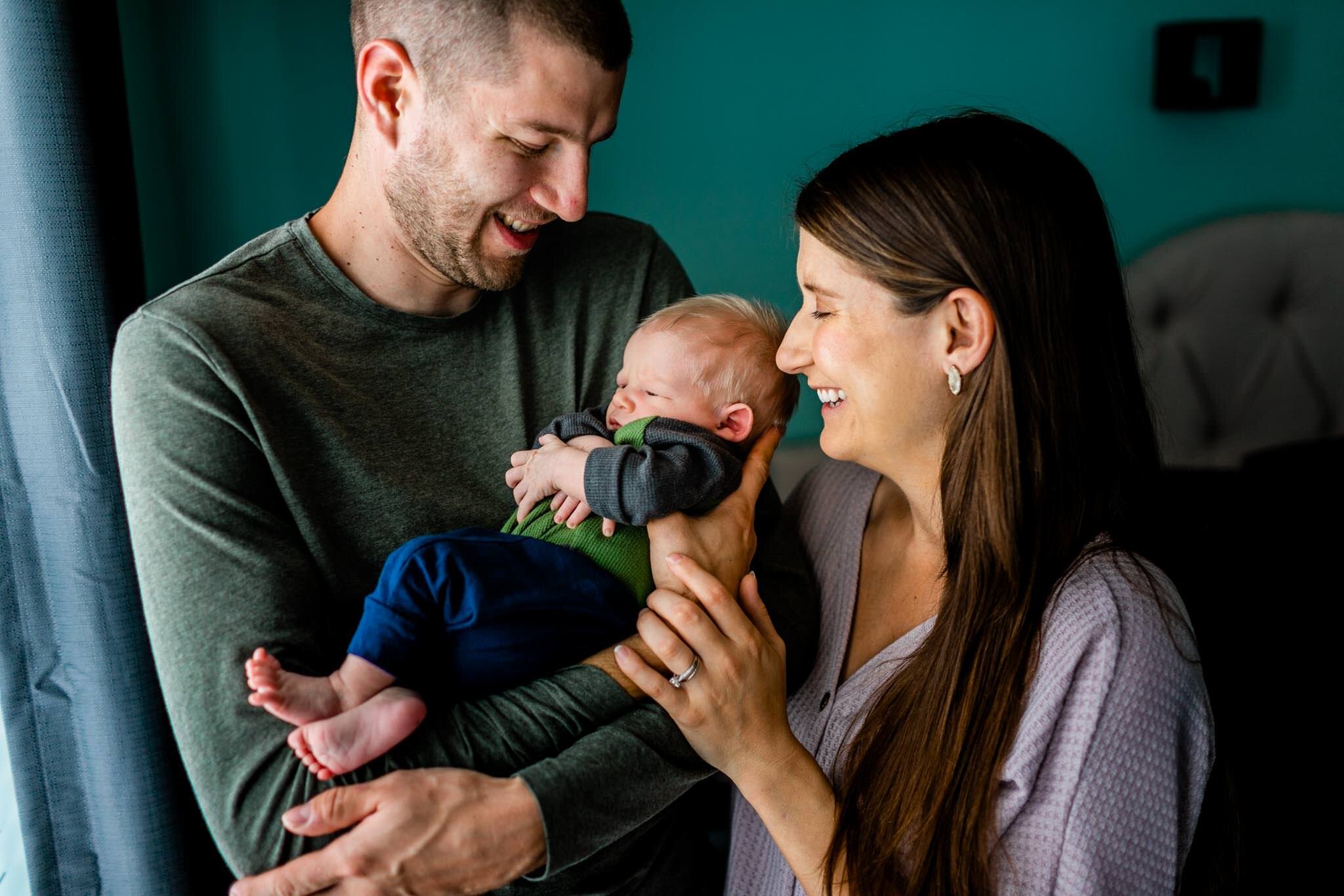 Durham Newborn Photographer | By G. Lin Photography | Father and mother holding baby and standing by window light
