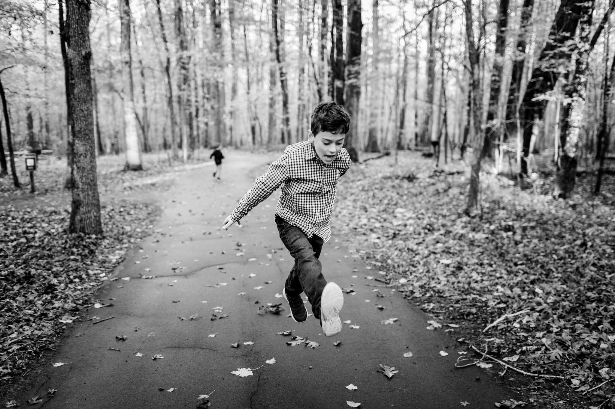 Raleigh Family Photographer | By G. Lin Photography | Umstead Park | Black and white photo of boy kicking legs in the air