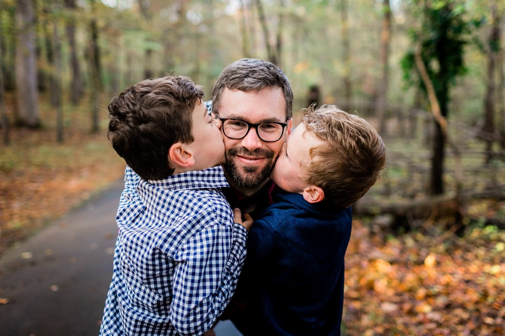 Raleigh Family Photographer | By G. Lin Photography | Umstead Park | Two sons kissing dad on the cheek