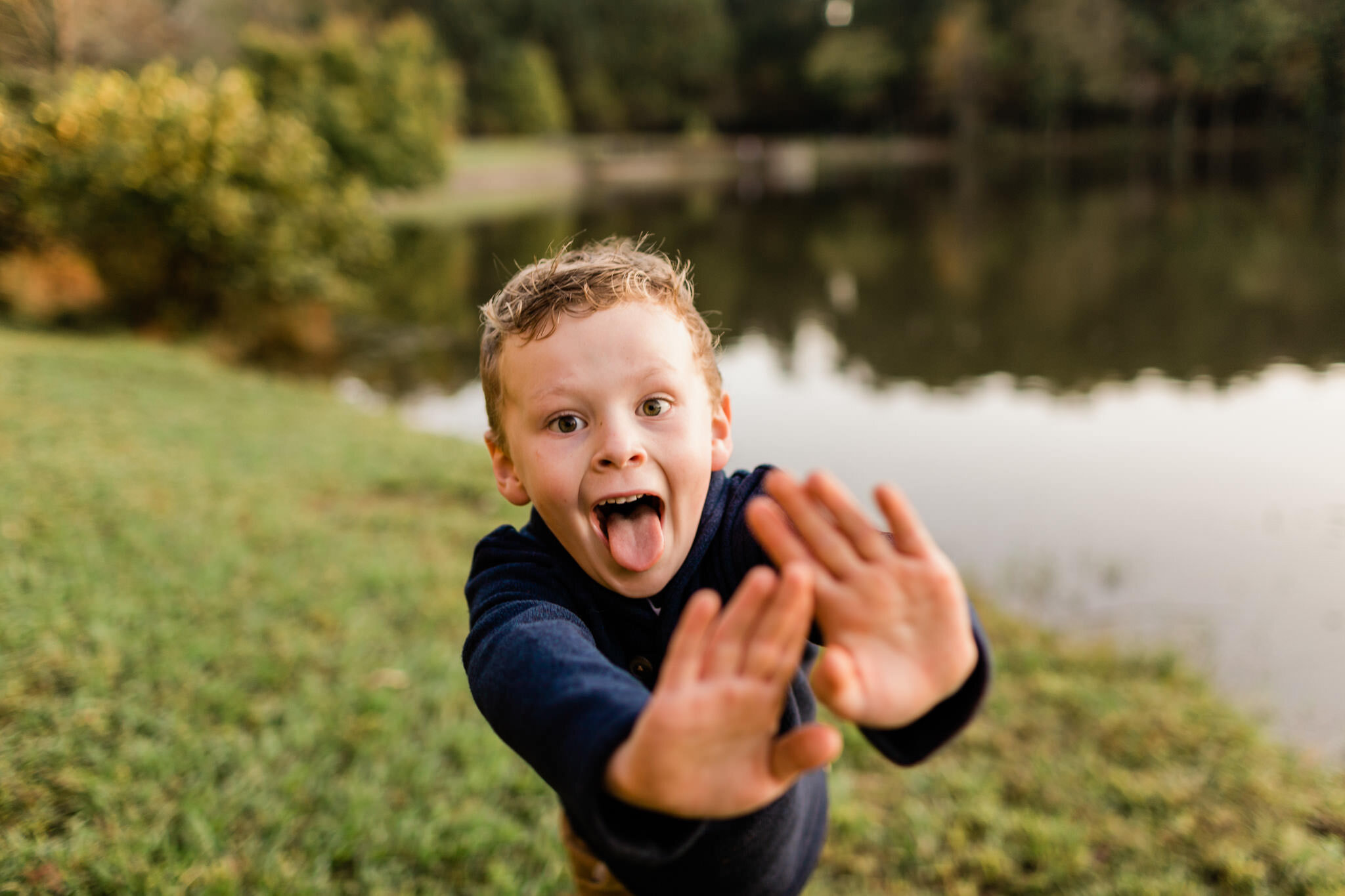 Raleigh Family Photographer | By G. Lin Photography | Umstead Park | Young boy making a funny face by the lake
