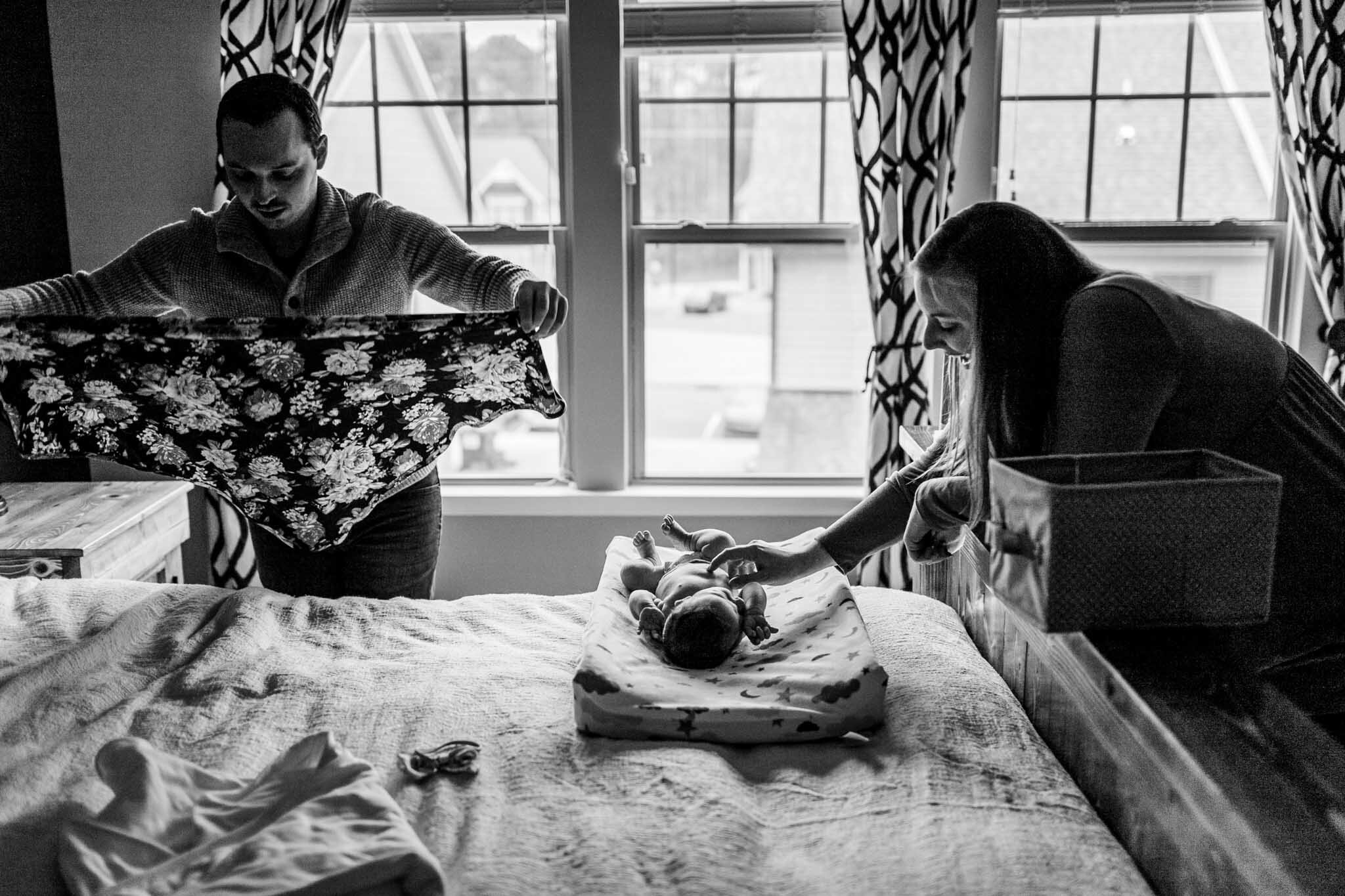 Durham Newborn Photographer | By G. Lin Photography | Black and white photo of parents changing diaper and swaddle