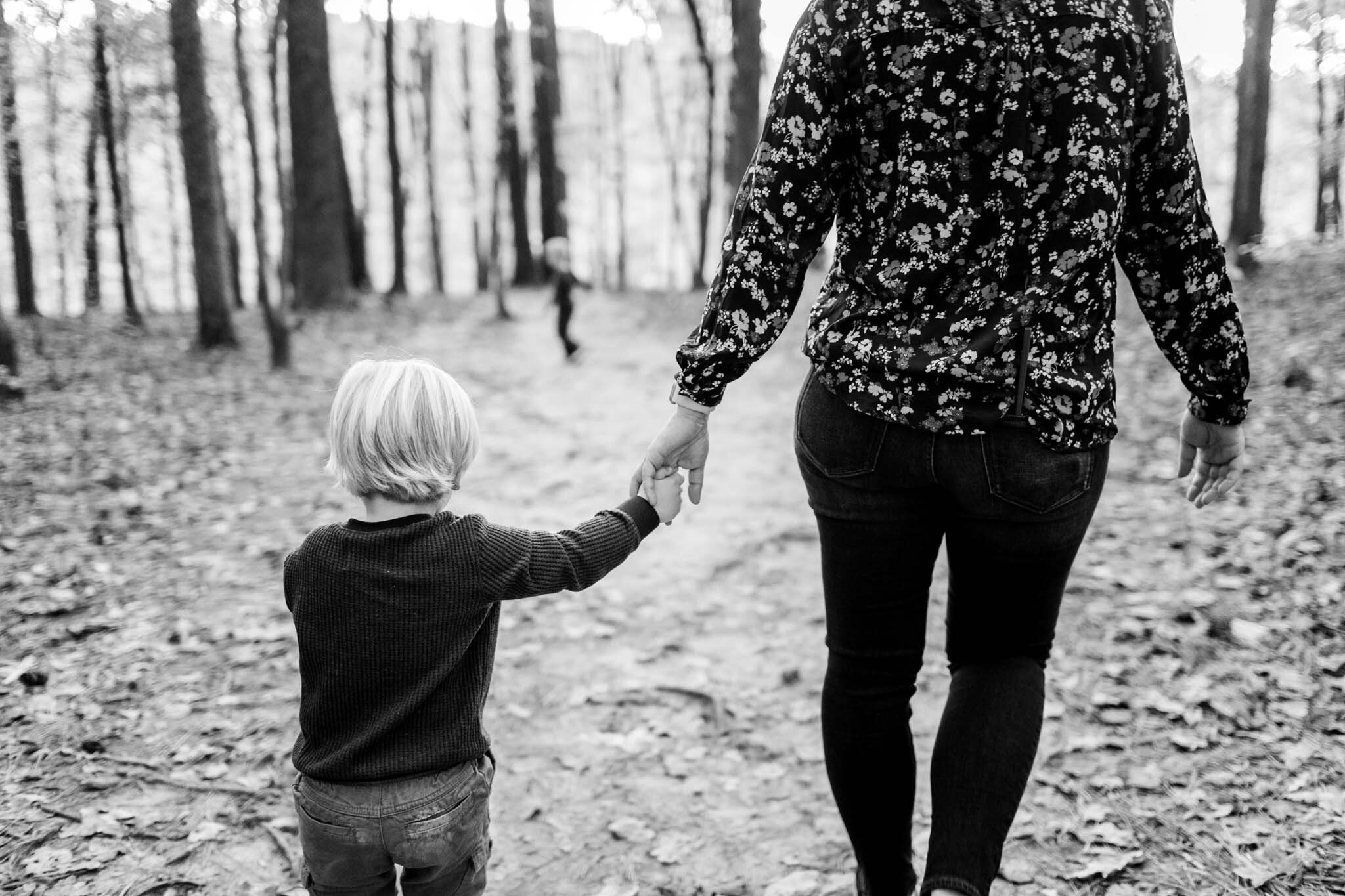 Raleigh Family Photographer at Umstead Park | By G. Lin Photography | Black and white photo of mom holding child's hand