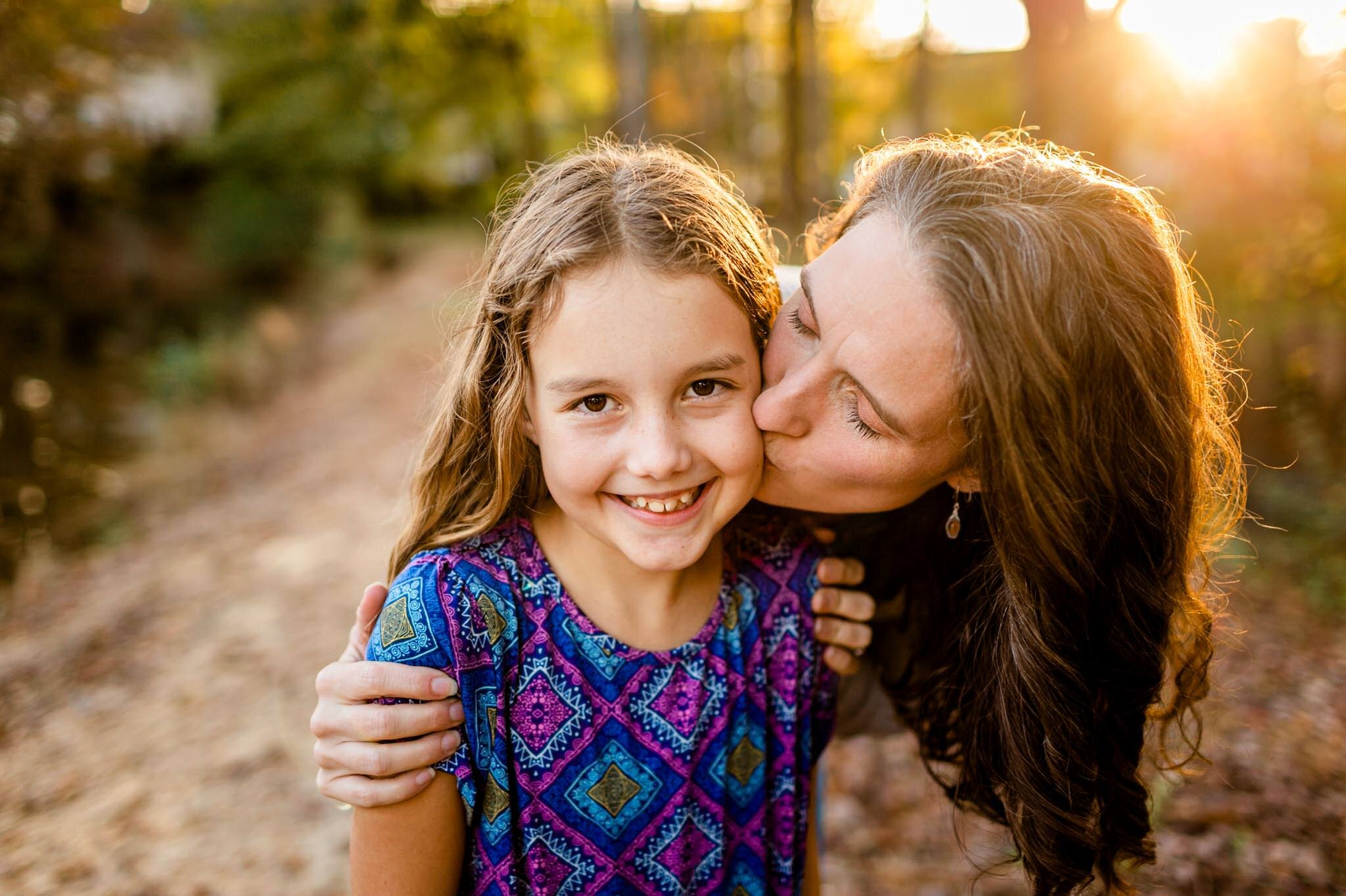 Apex Family Photographer | By G. Lin Photography | Mother kissing daughter on cheek with golden light behind them