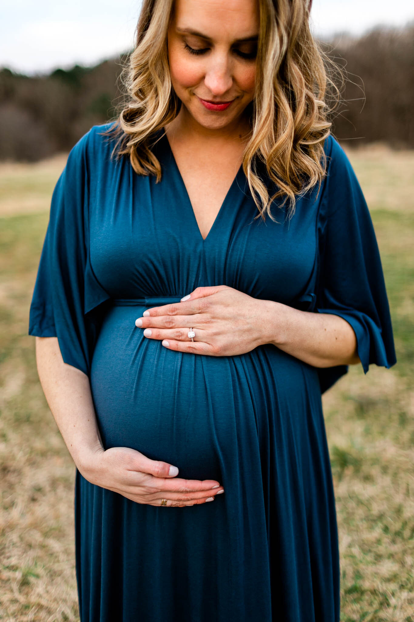 Raleigh Newborn Photographer | By G. Lin Photography | Gorgeous maternity portrait of woman in blue dress with hands on baby bump
