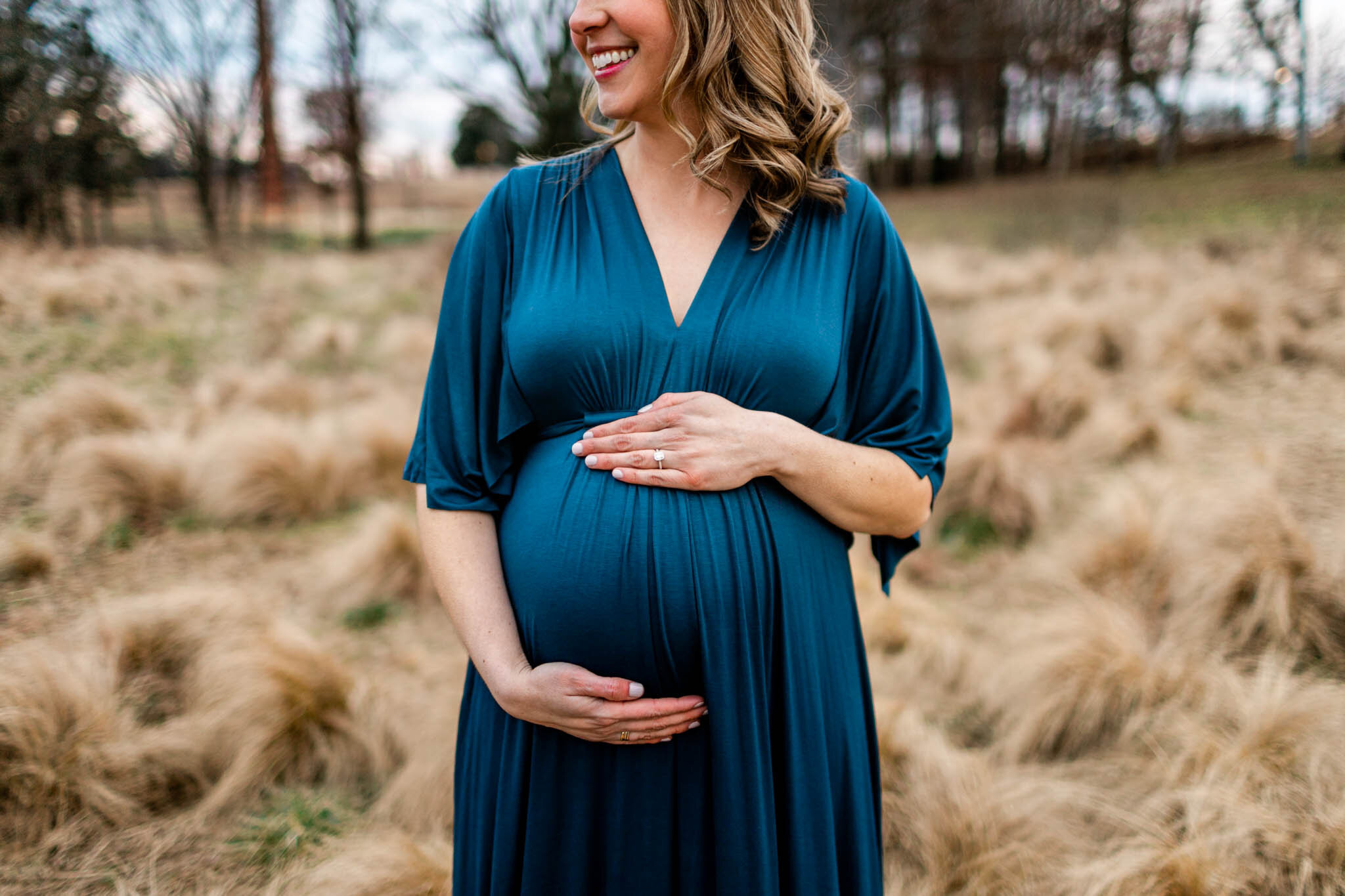 Raleigh Newborn Photographer | By G. Lin Photography | Woman smiling with hands on baby bump at NCMA
