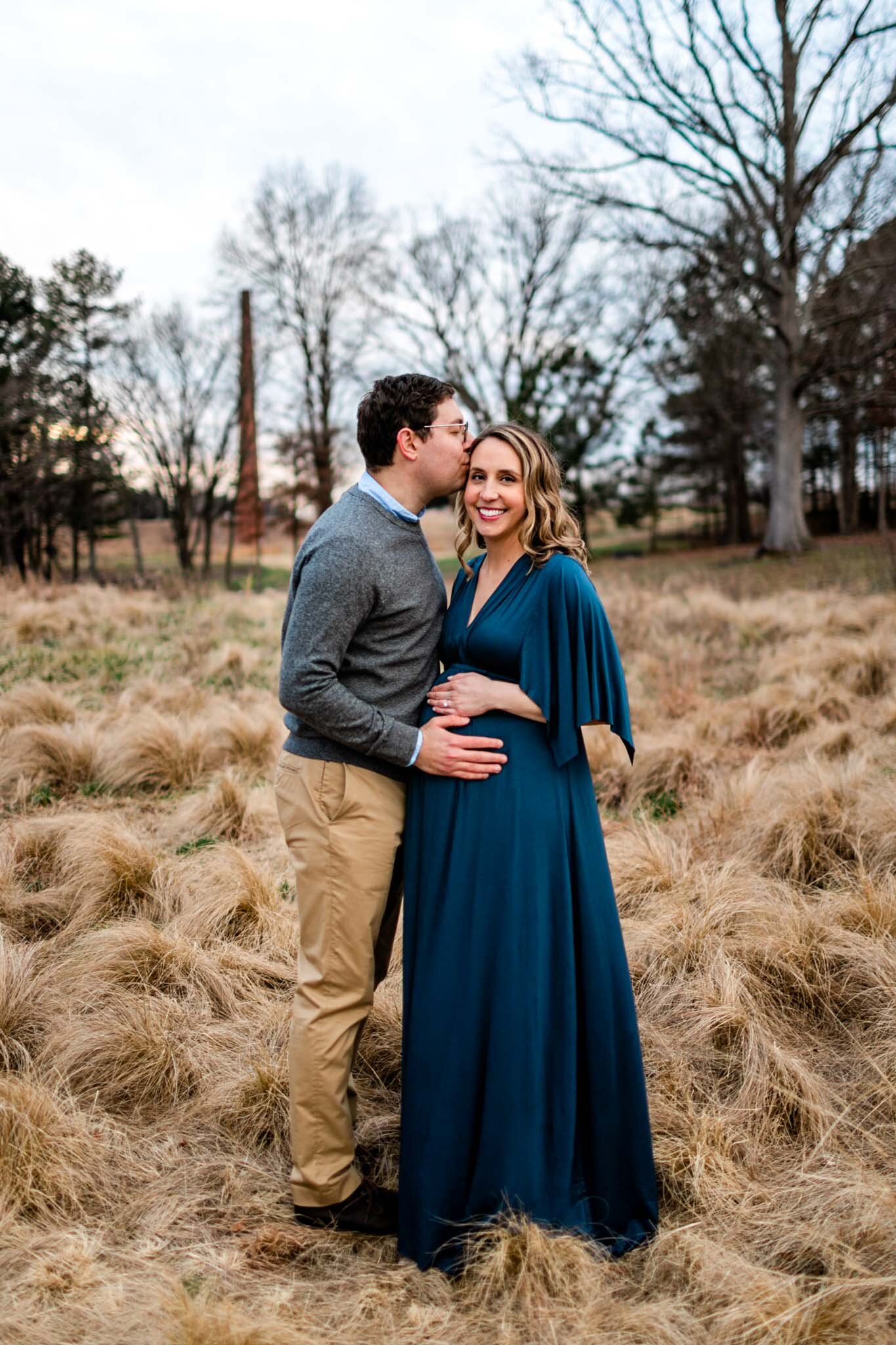 Raleigh Newborn Photographer | By G. Lin Photography | Man kissing woman on cheek and standing in open field at NCMA