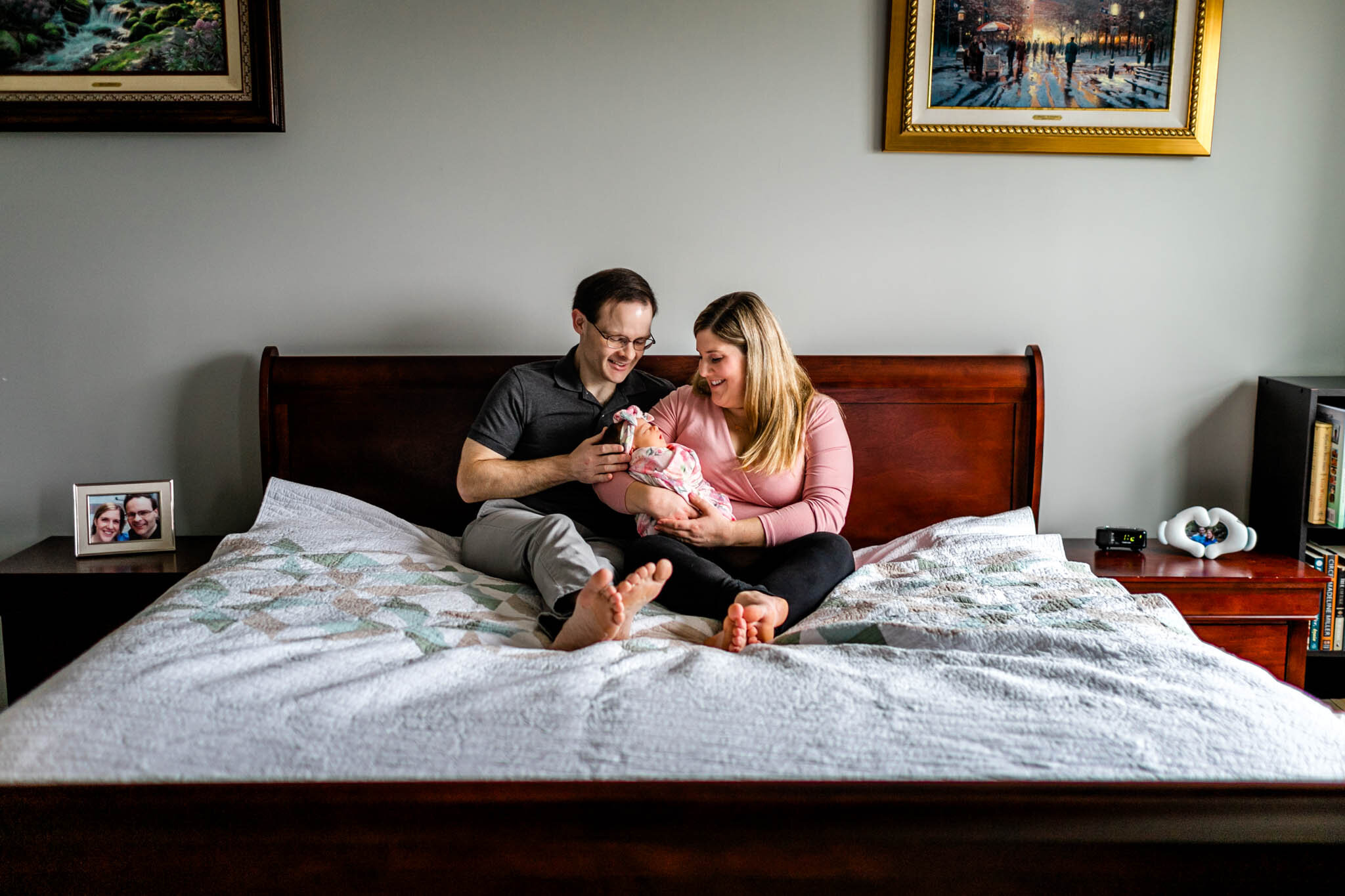 Raleigh Newborn Photographer | By G. Lin Photography | Father and mother sitting on bed with baby girl