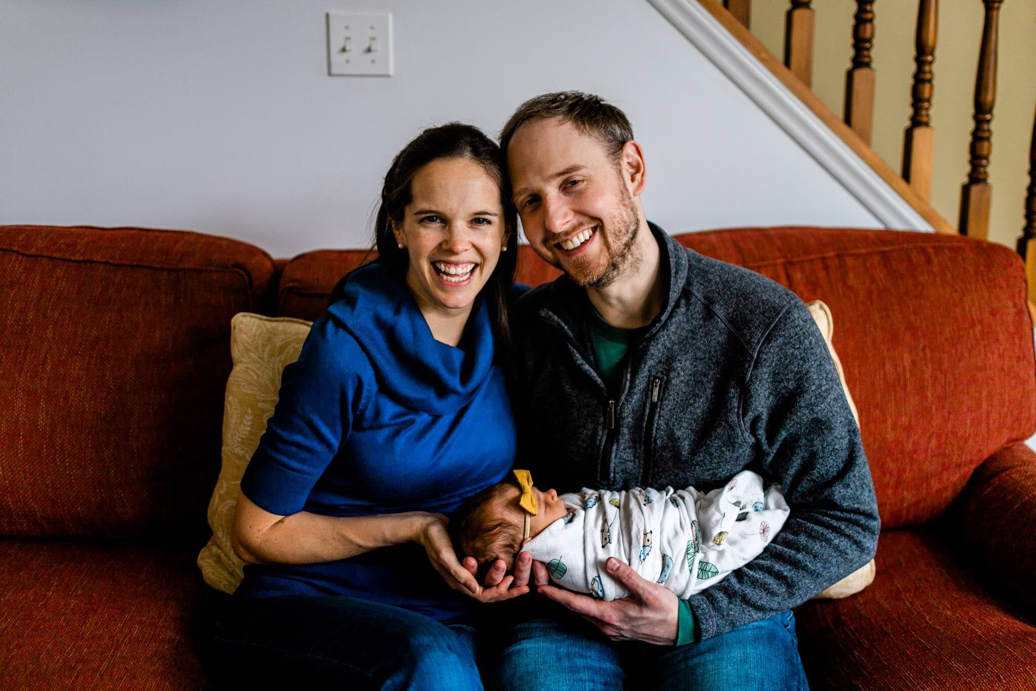 Durham Newborn Photographer | By G. Lin Photography | Husband and wife sitting on red couch while holding baby