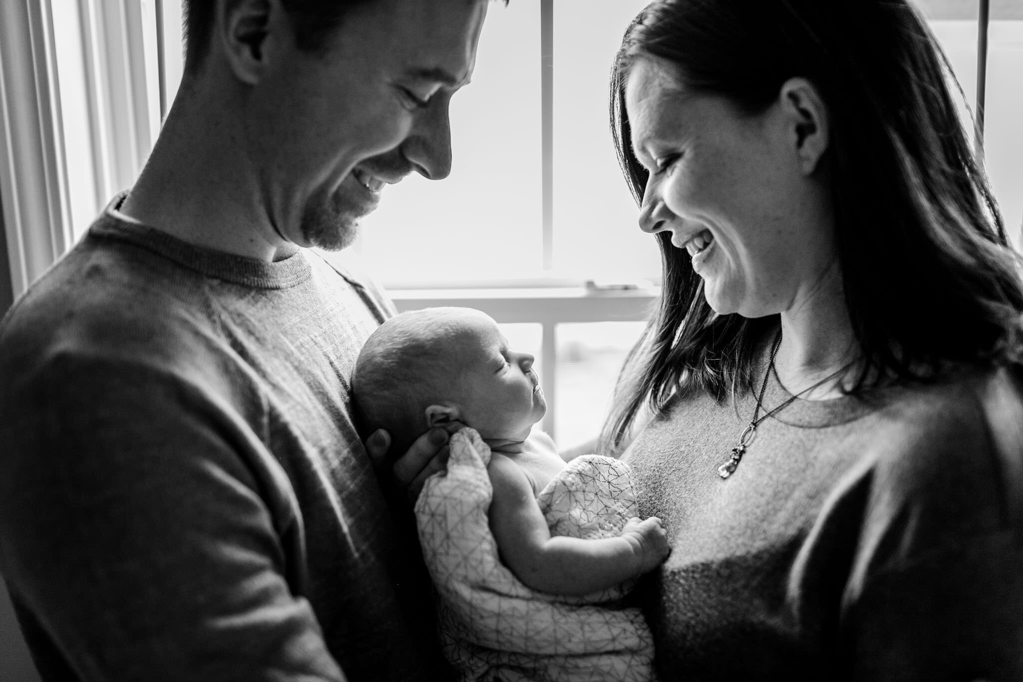 Hillsborough Newborn Photographer | By G. Lin Photography | Black and white photo of mom and dad holding baby by light
