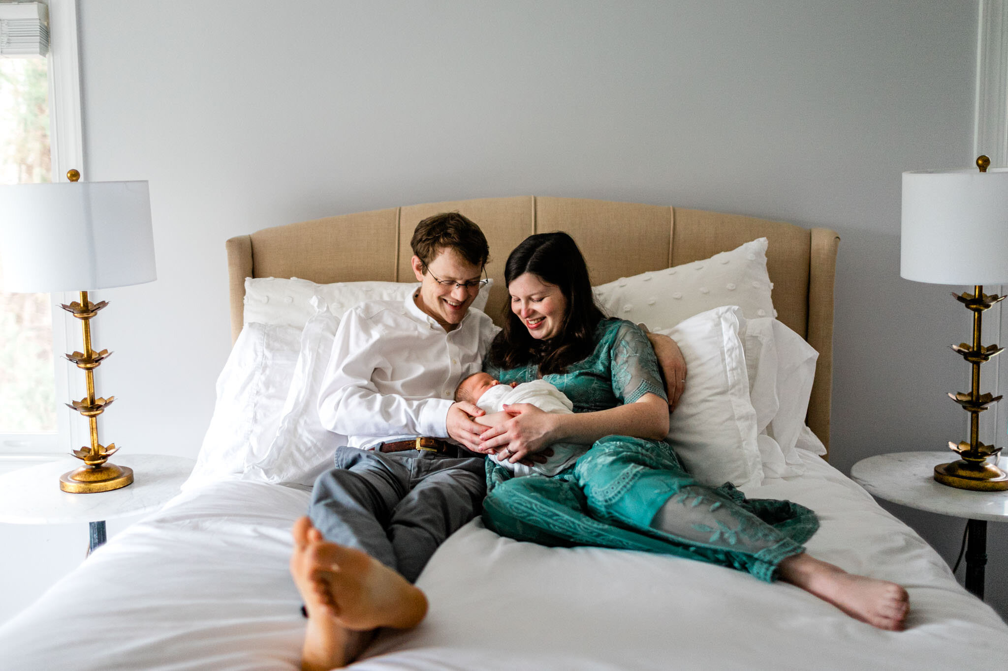 Durham Newborn Photographer | By G. Lin Photography | Man and woman holding baby and sitting on bed