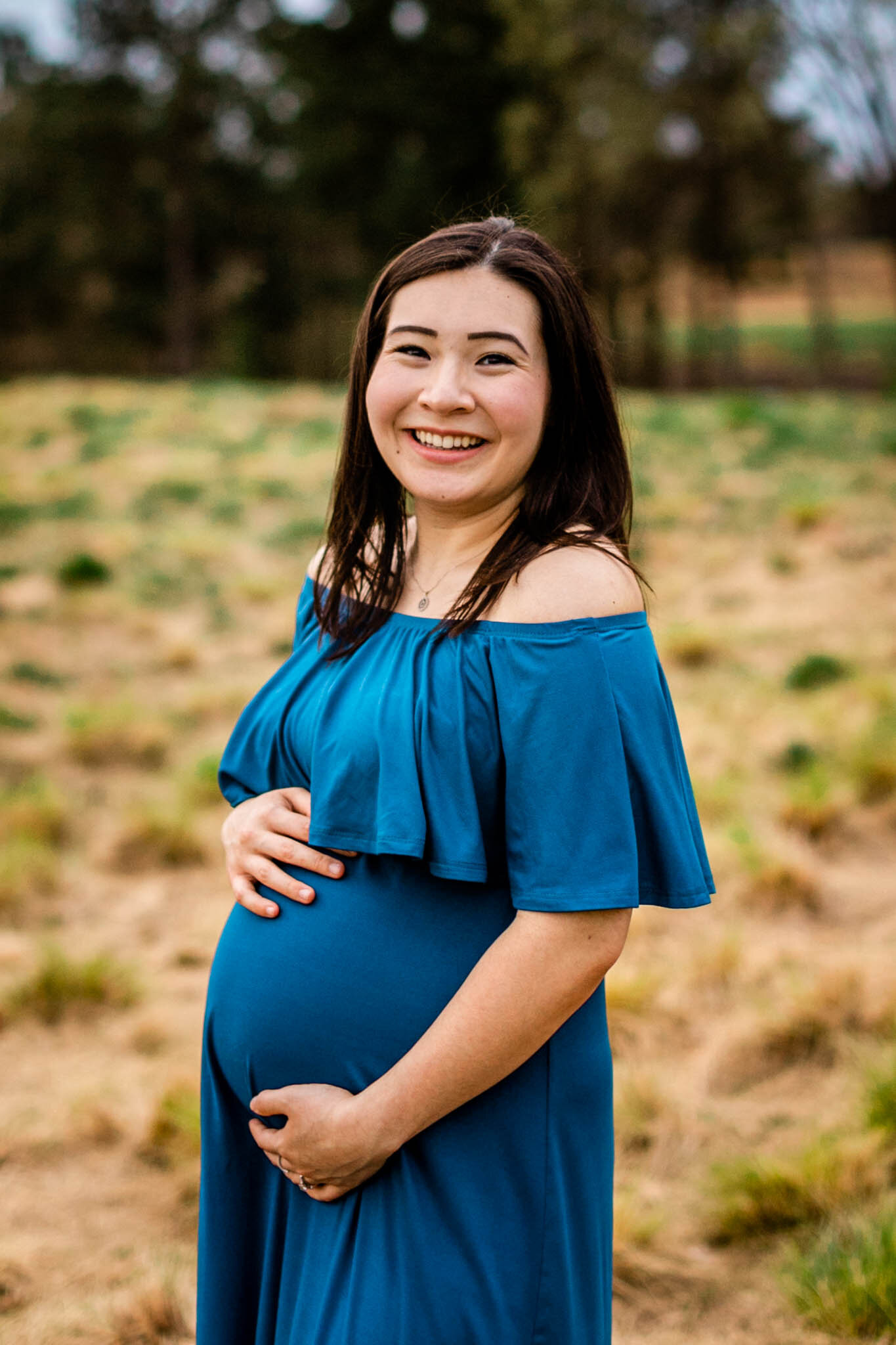 Raleigh Maternity Photographer | By G. Lin Photography | NC Museum of Art | Woman smiling with hands on baby bump