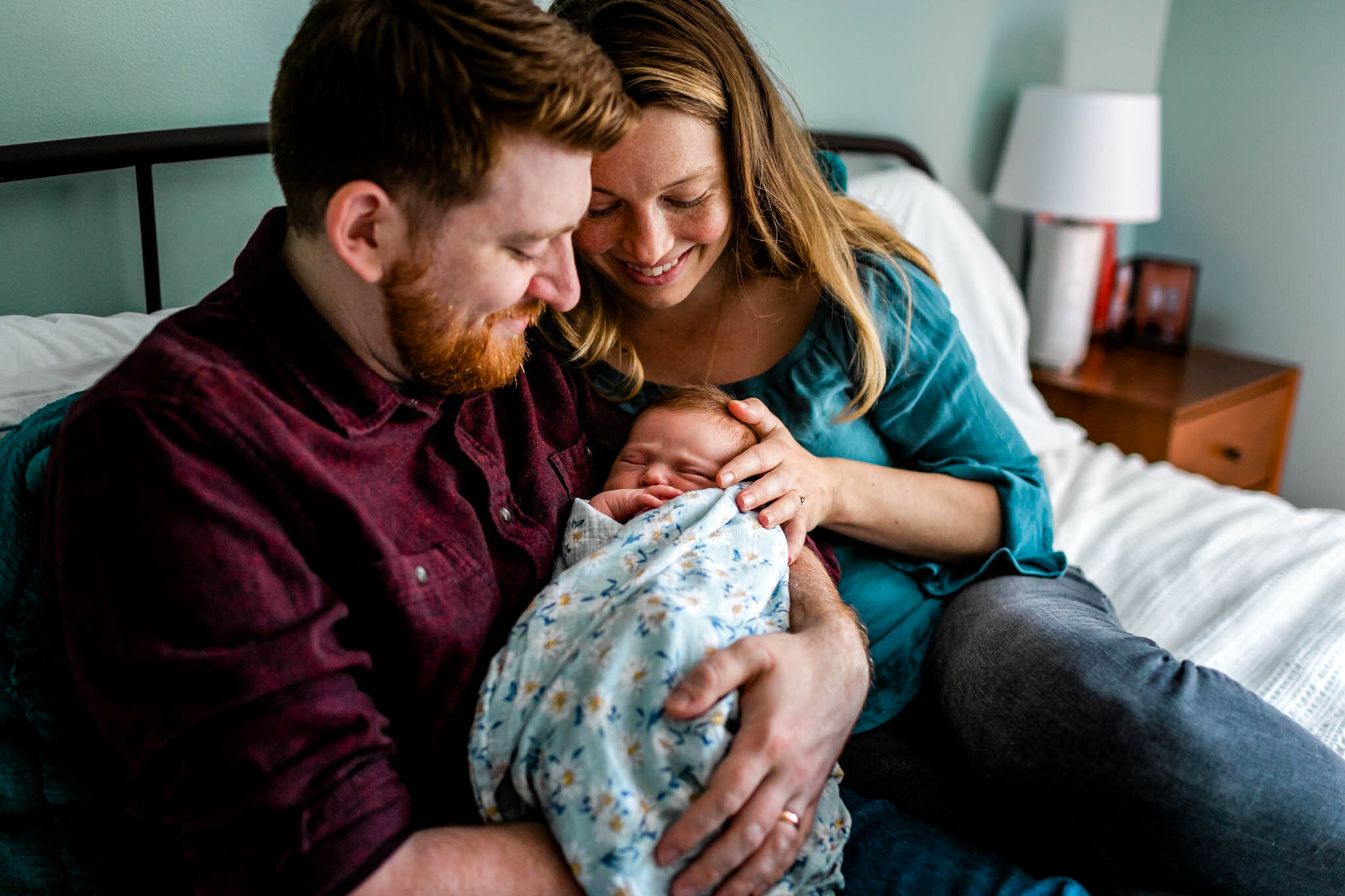 Durham Newborn Photographer | By G. Lin Photography | Mother and father holding baby girl on bed