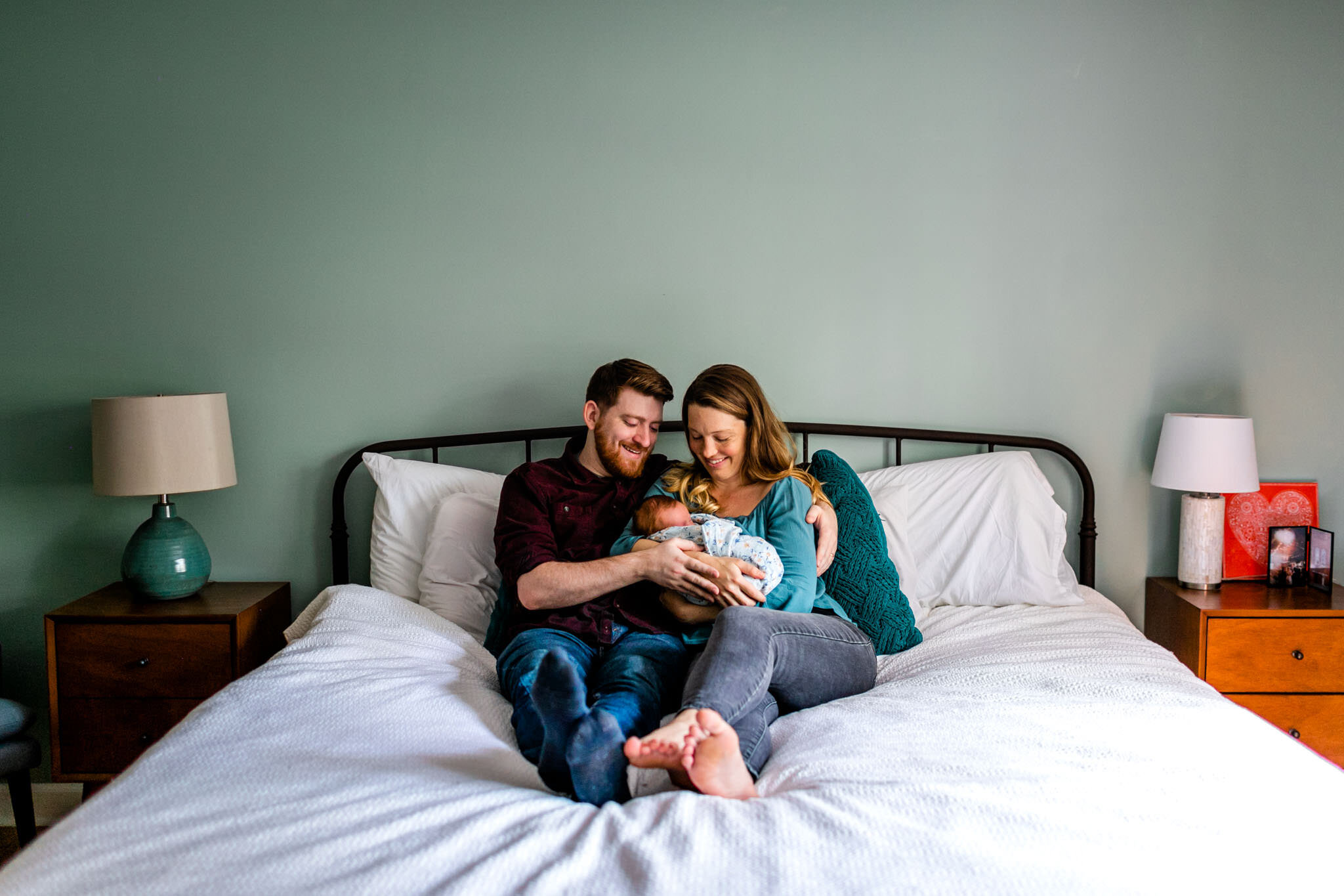 Durham Newborn Photographer | By G. Lin Photography | New parents sitting on bed with baby girl