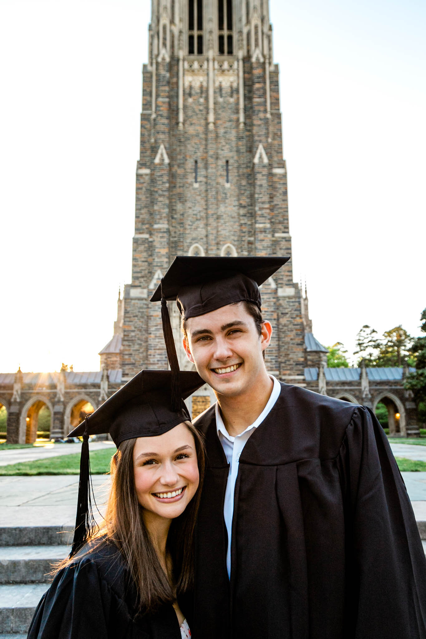Graduates wearing black cap and gown in front of Duke Chapel during sunset | Durham Senior Photographer | By G. Lin Photography