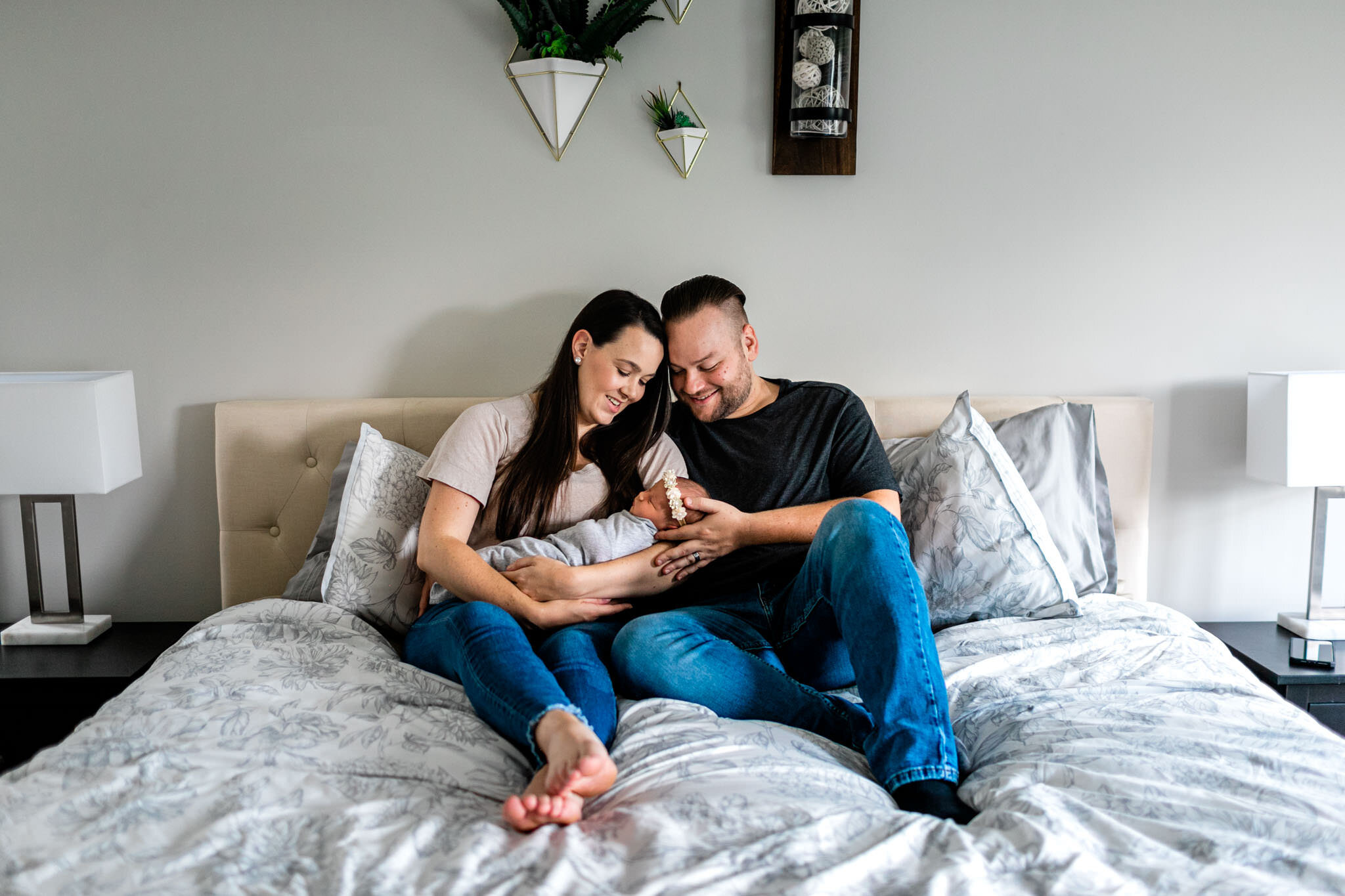 Parents sitting on bed and smiling at baby | Holly Spring Newborn Photographer | By G. Lin Photography