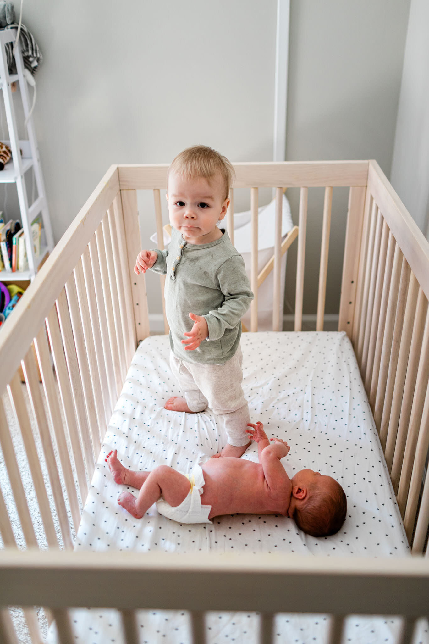 Toddler boy standing in crib with baby sister | Holly Spring Newborn Photographer | By G. Lin Photography